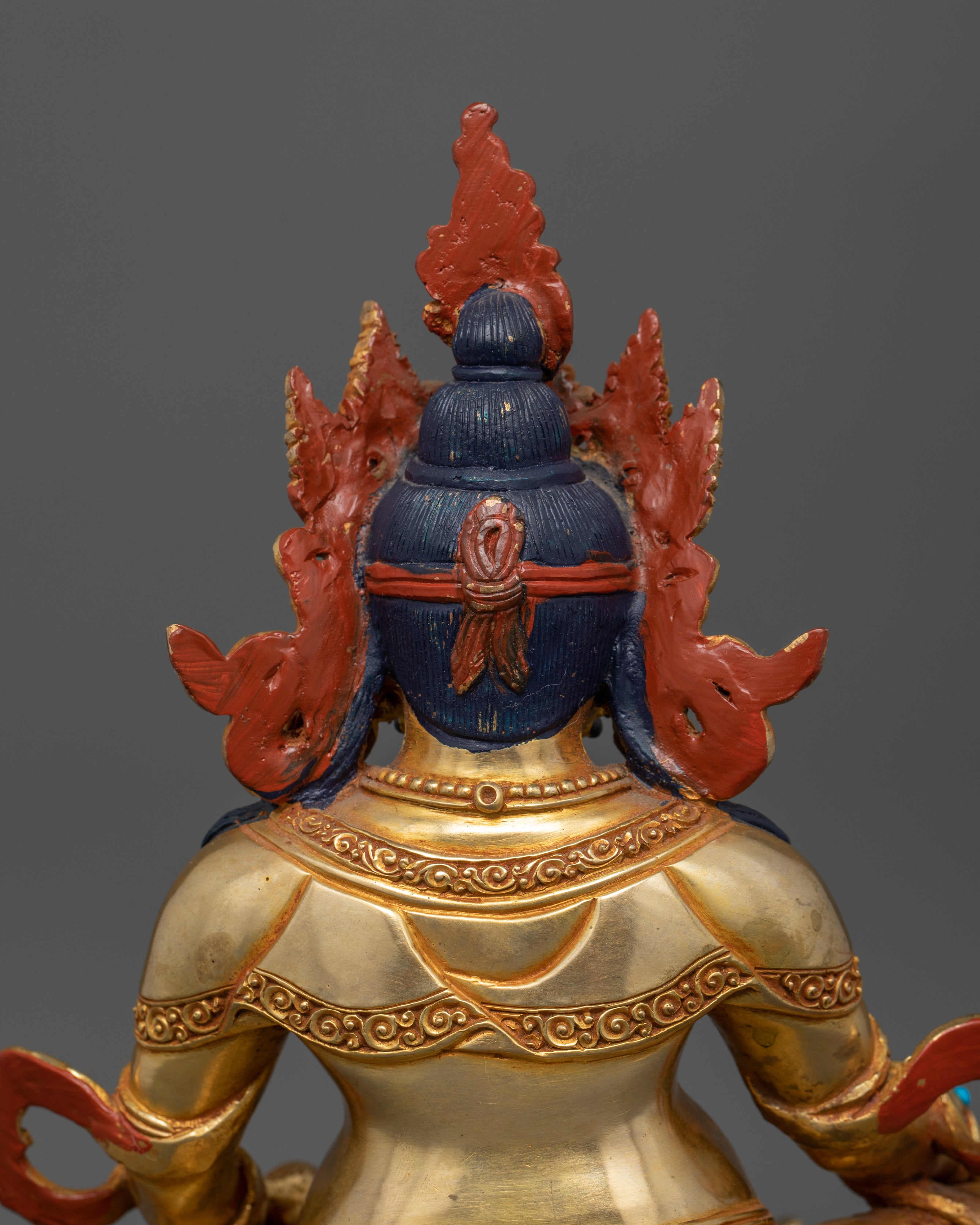 view of Dzambhala’s upper side, showcasing the intricate patterns on his robe and the fine detailing of his ornate crown without a halo.