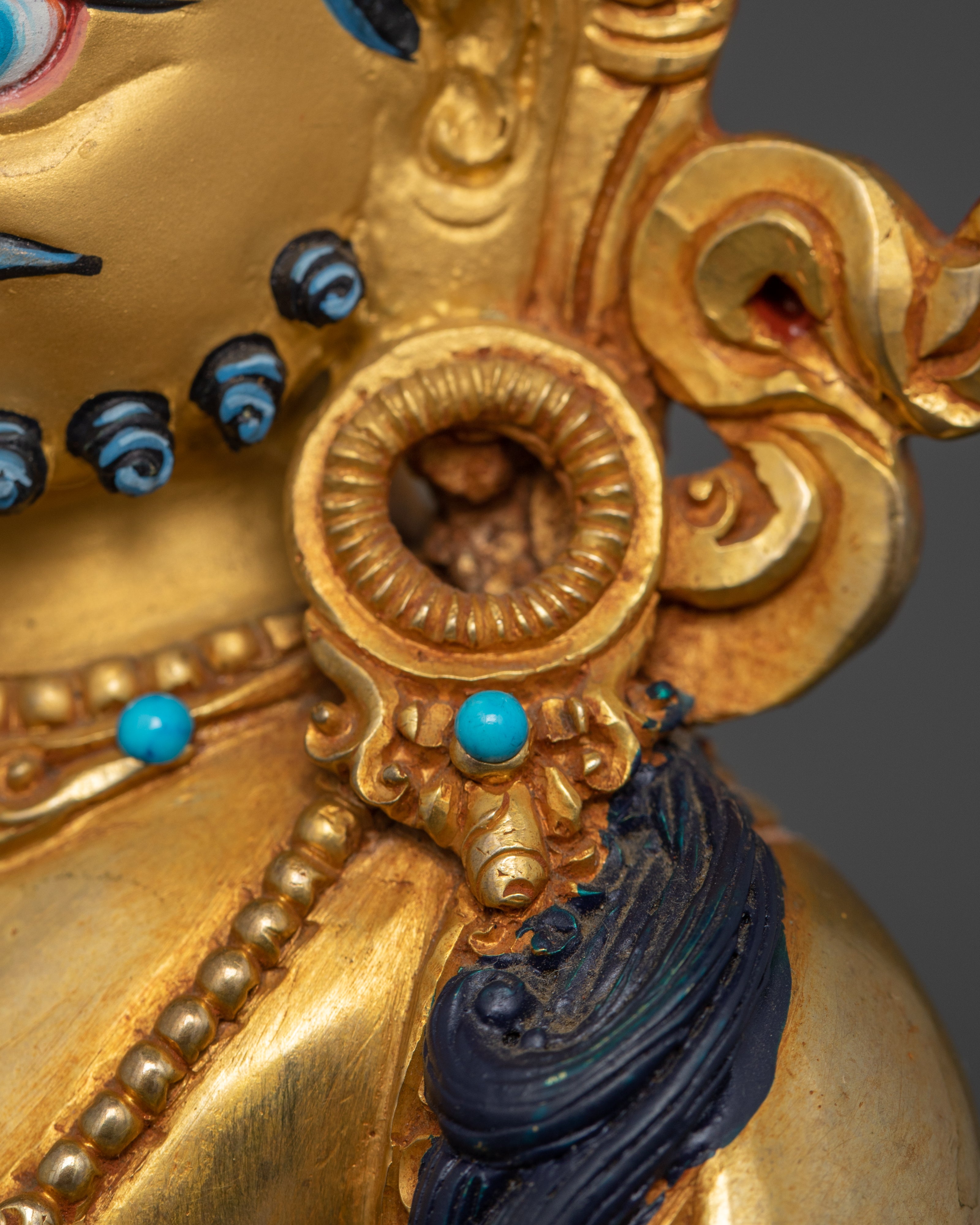 Close-up view of Dzambhala’s left ear adorned with a jewel, enhancing the deity’s regal appearance.
