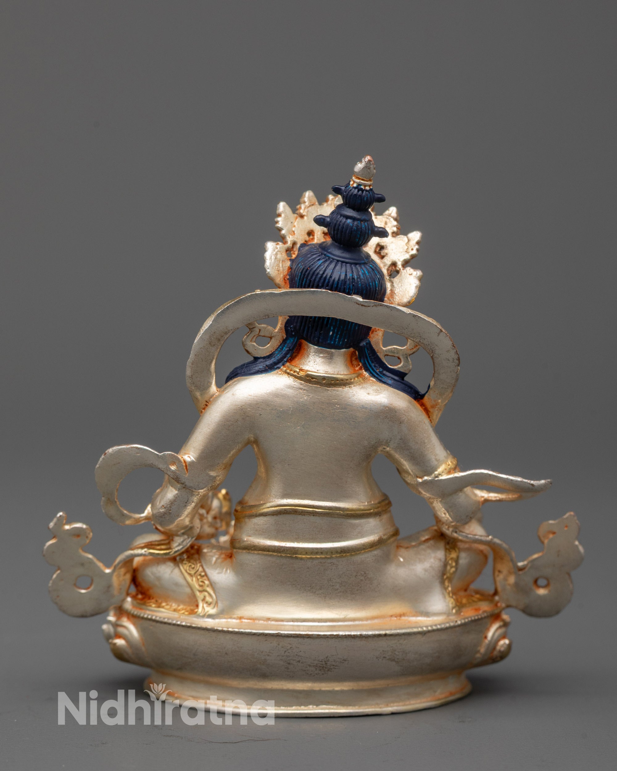 Dzambhala seated on silver-plated lotus seat with foot resting on a shell, front view