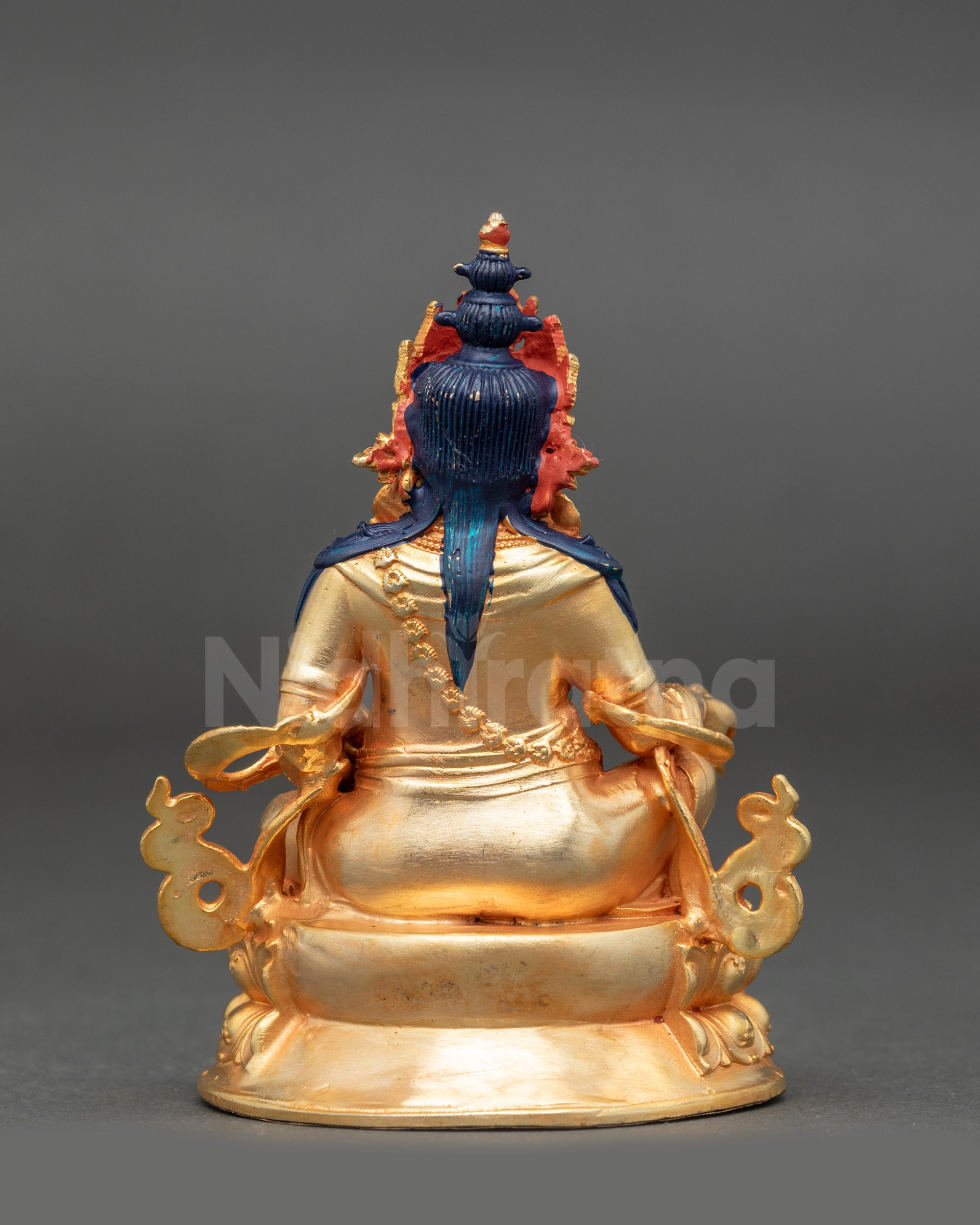 Dzambhala statue with gold painted face and fire-gilded body holding mongoose and citron