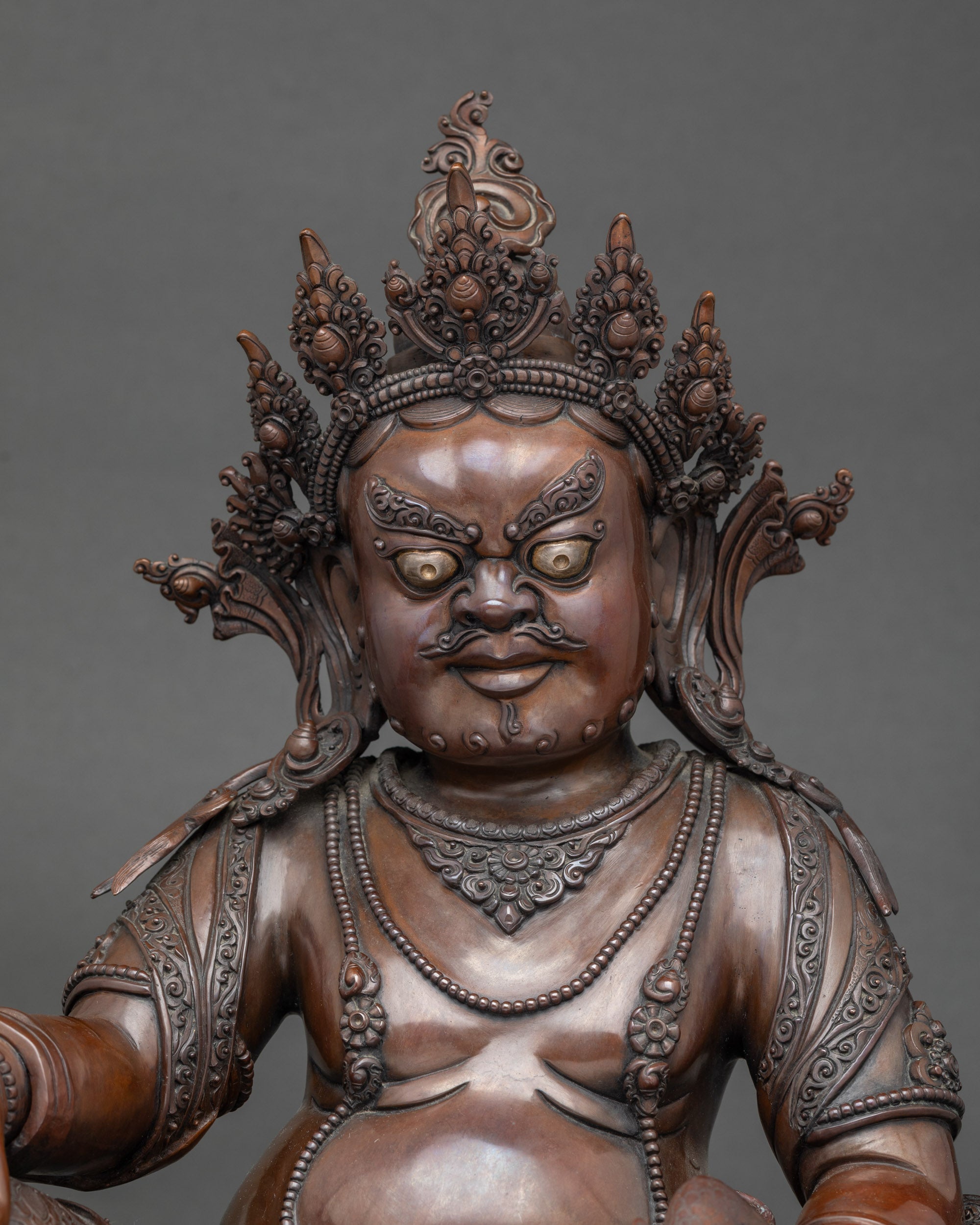 Close up Dzambhala Buddha face with five-point crown and jewelry, handcrafted Nepalese art