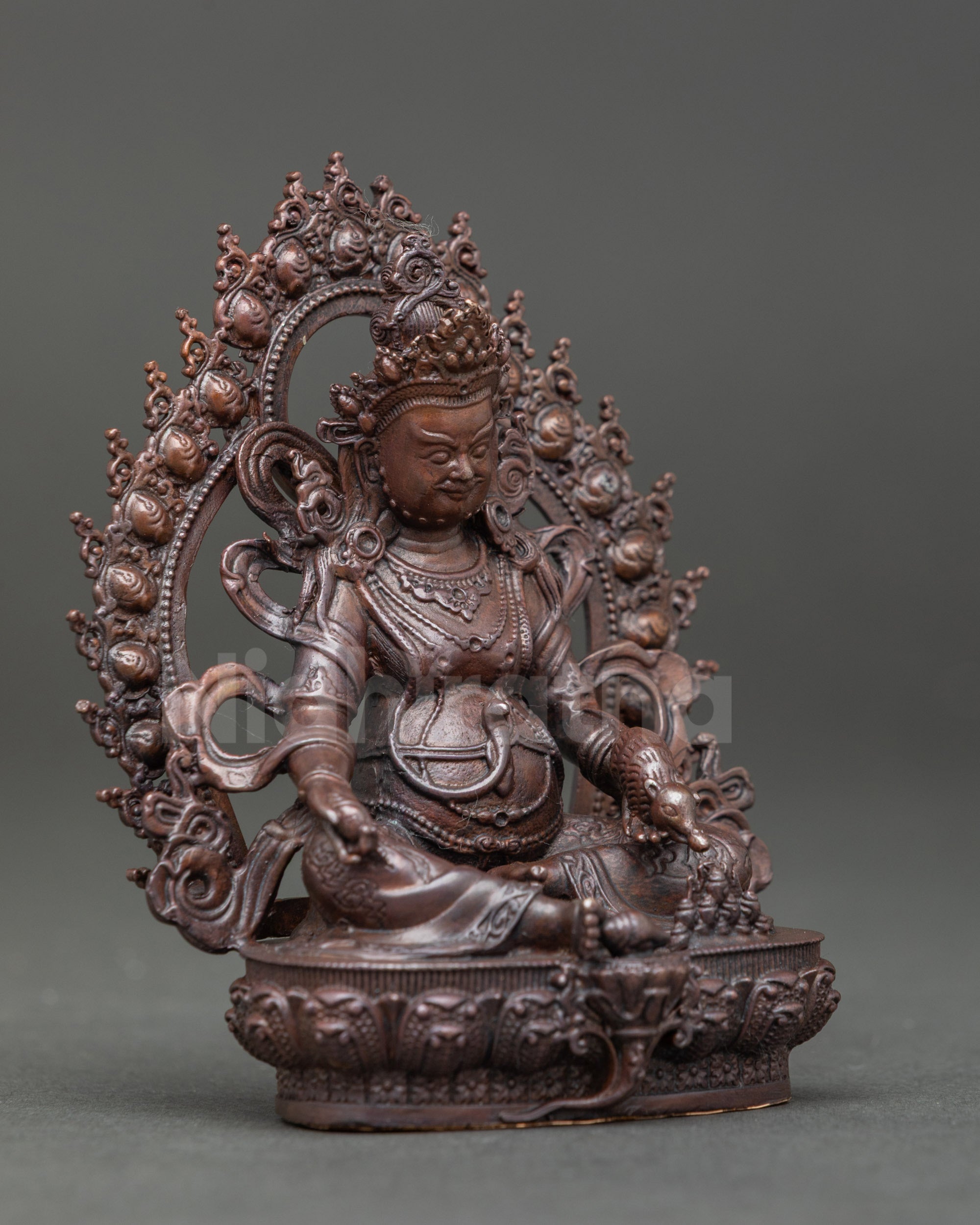 Side view of Dzambhala statue showing intricate details of lotus seat and deity posture