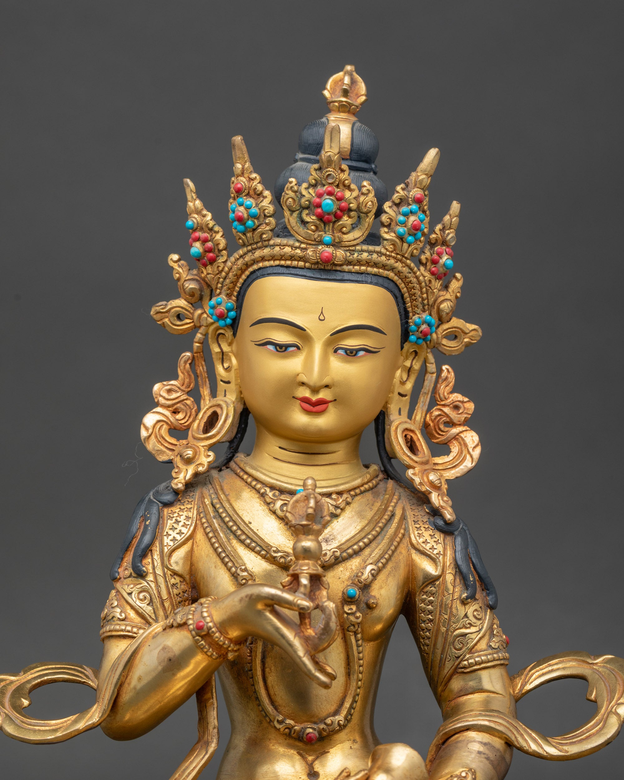 Close-up of Vajrasattva Buddha holding vajra and bell, detailed gold-painted face