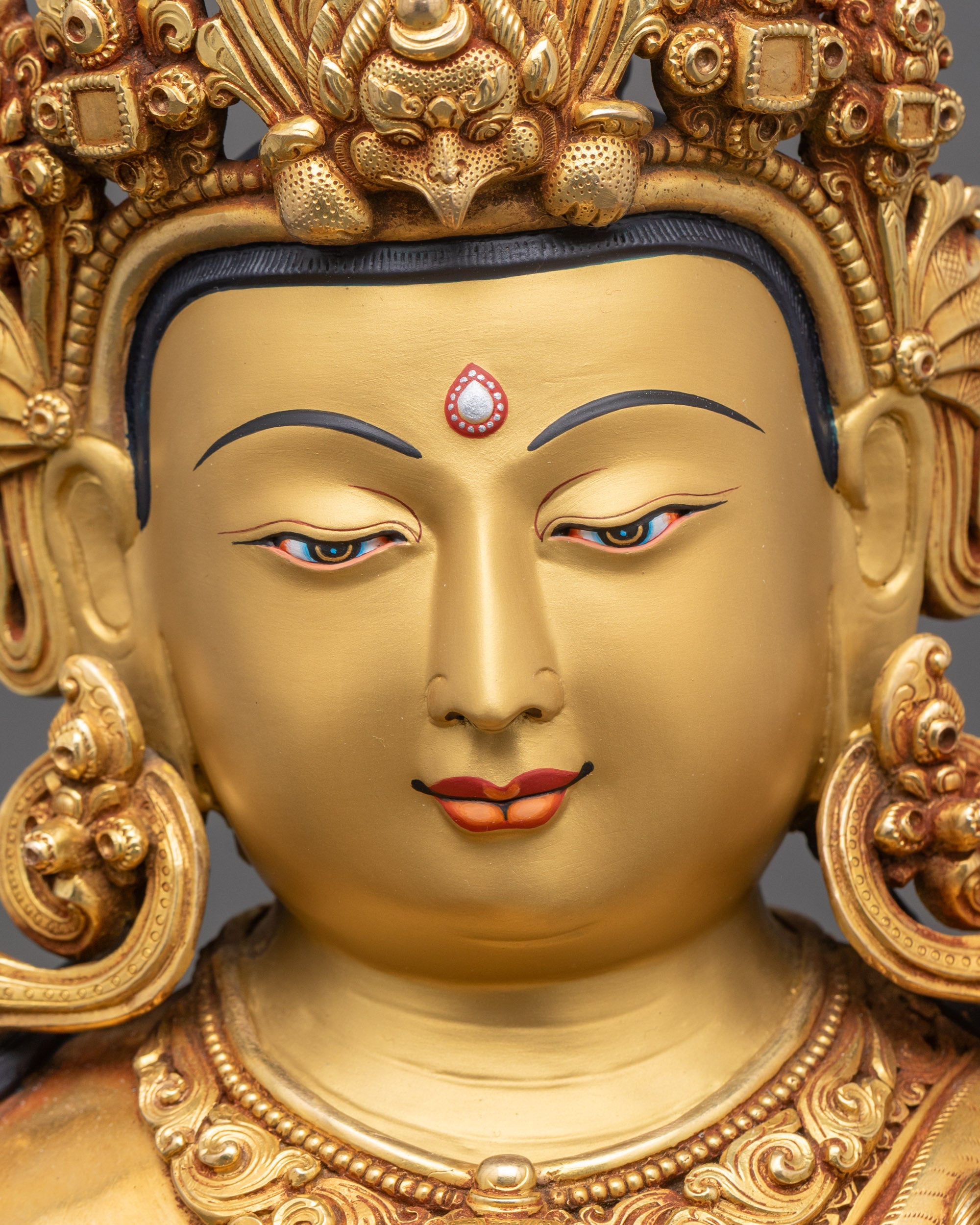 Face close-up of Chenrezig with serene gold-painted expression and crown