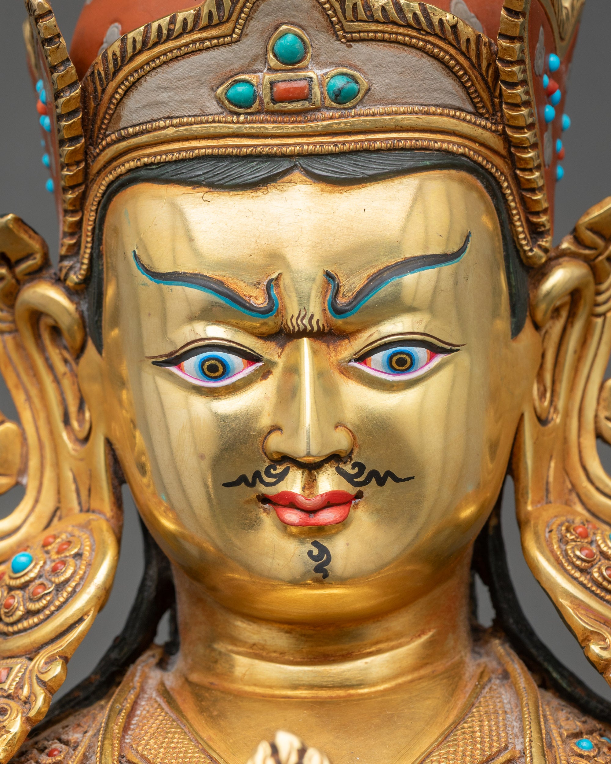 Face close-up of Guru Norlha with lotus hat, semi-precious stones, and gold accents