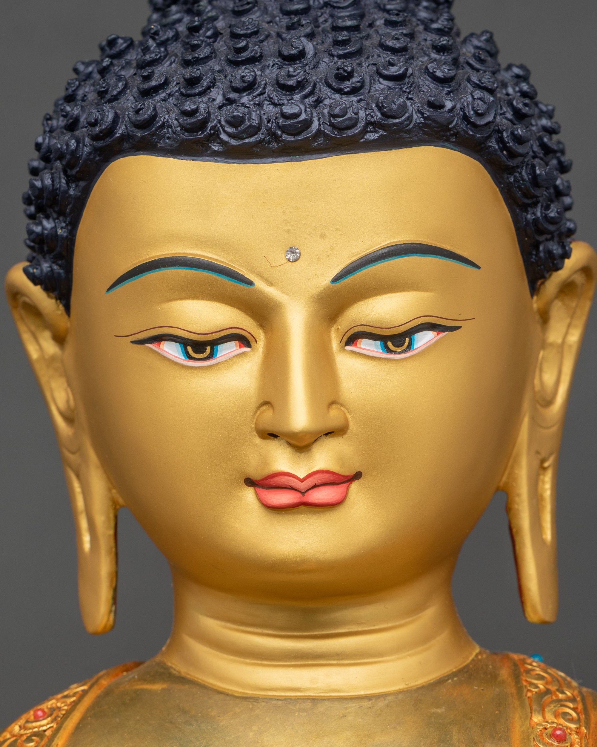Face close up of Shakyamuni Buddha with deep blue eyes and gold painted face