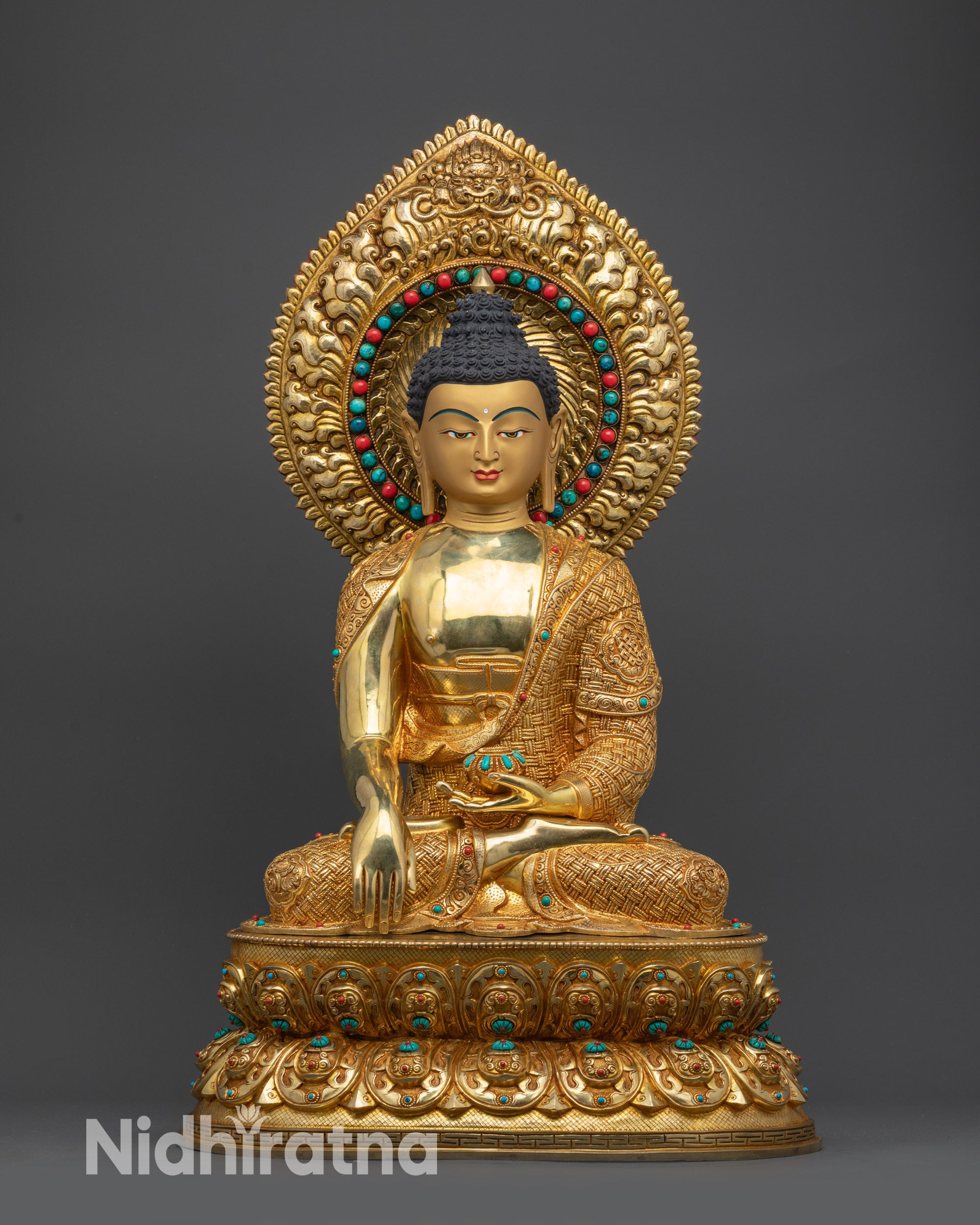 Front view of Shakyamuni Buddha statue gold-gilded with lotus pedestal and halo