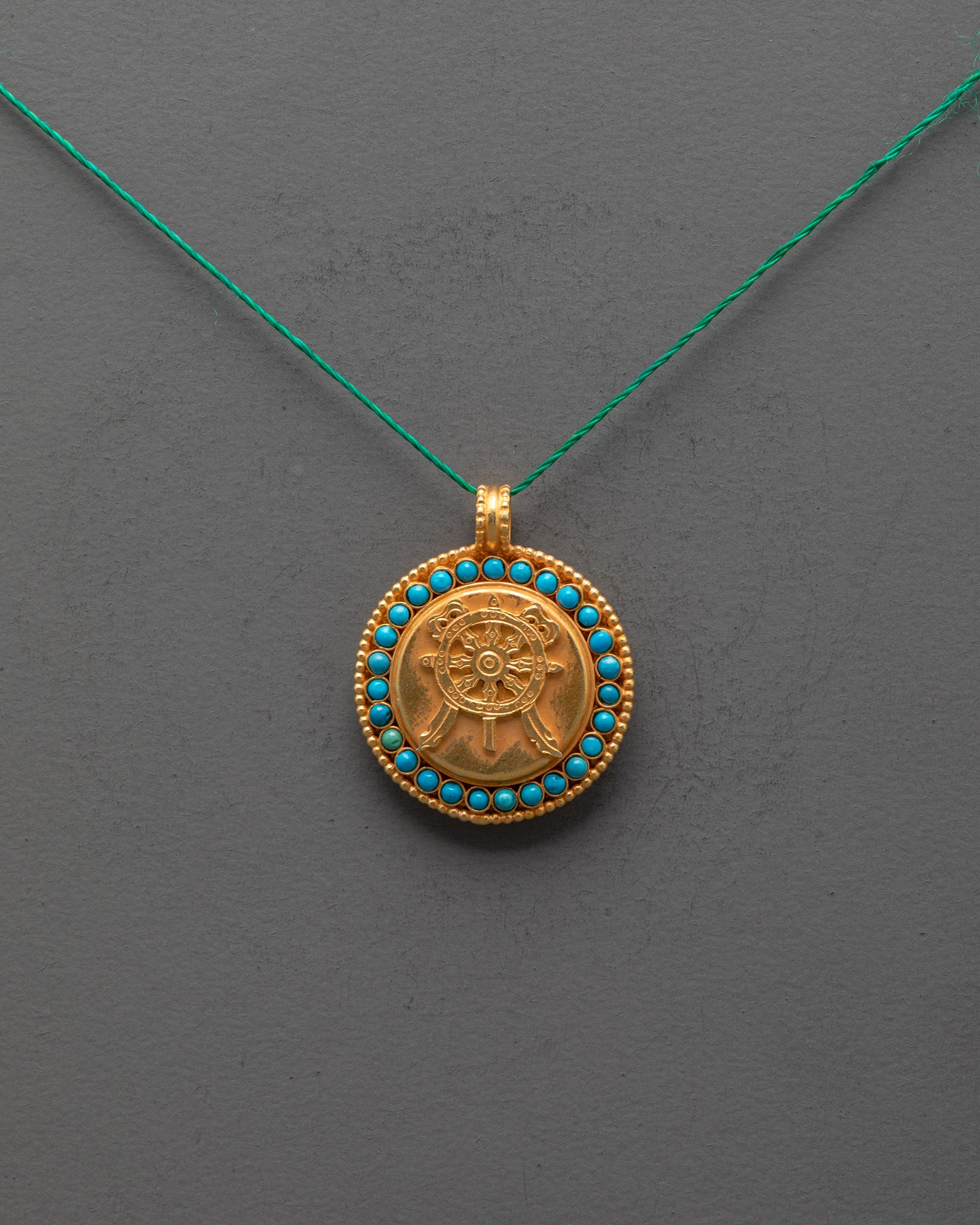 Front view of gold-plated Dharma Wheel Locket with filigree and semi-precious stones