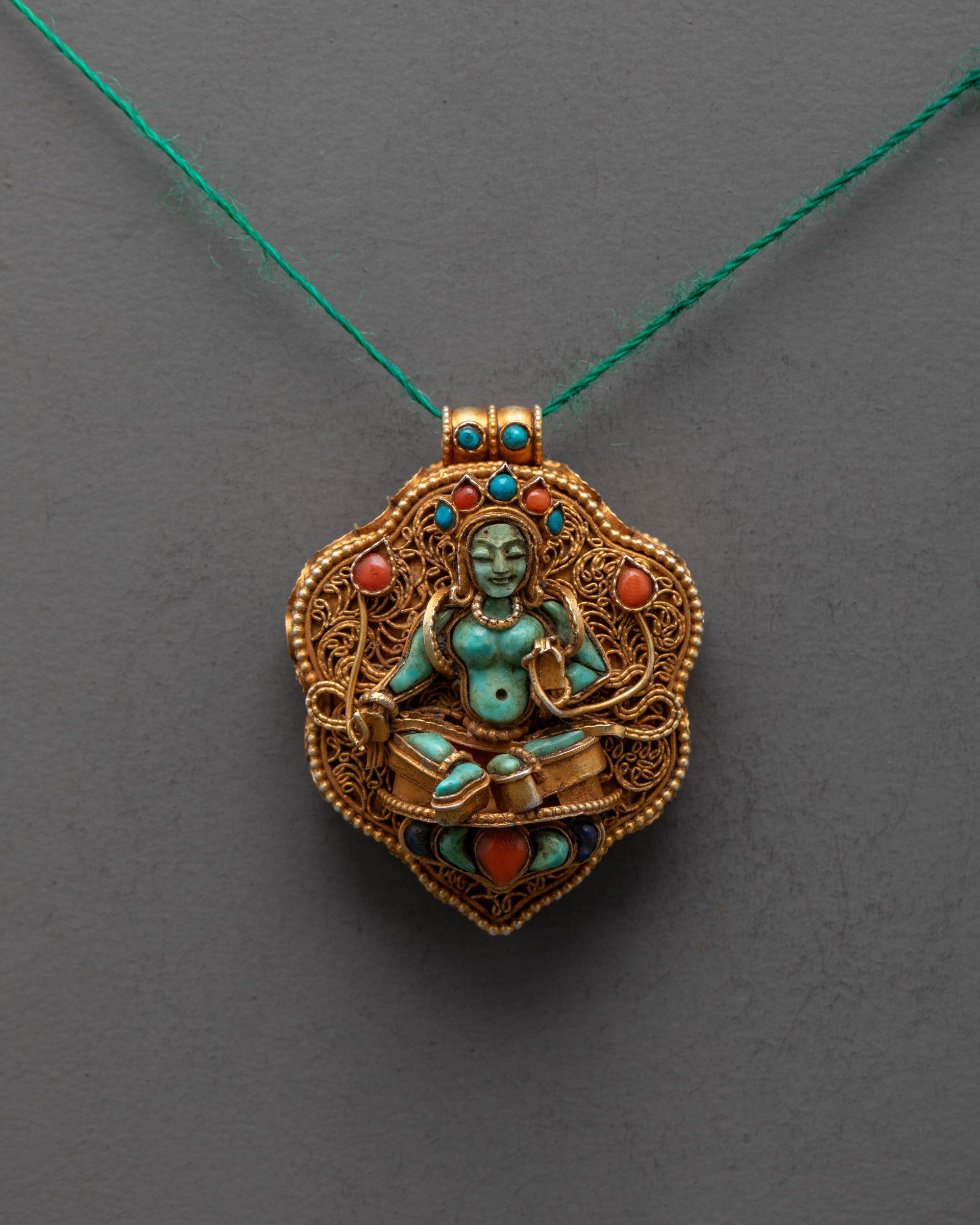 Front view of gold-plated Green Tara locket pendant with turquoise figure and filigree design