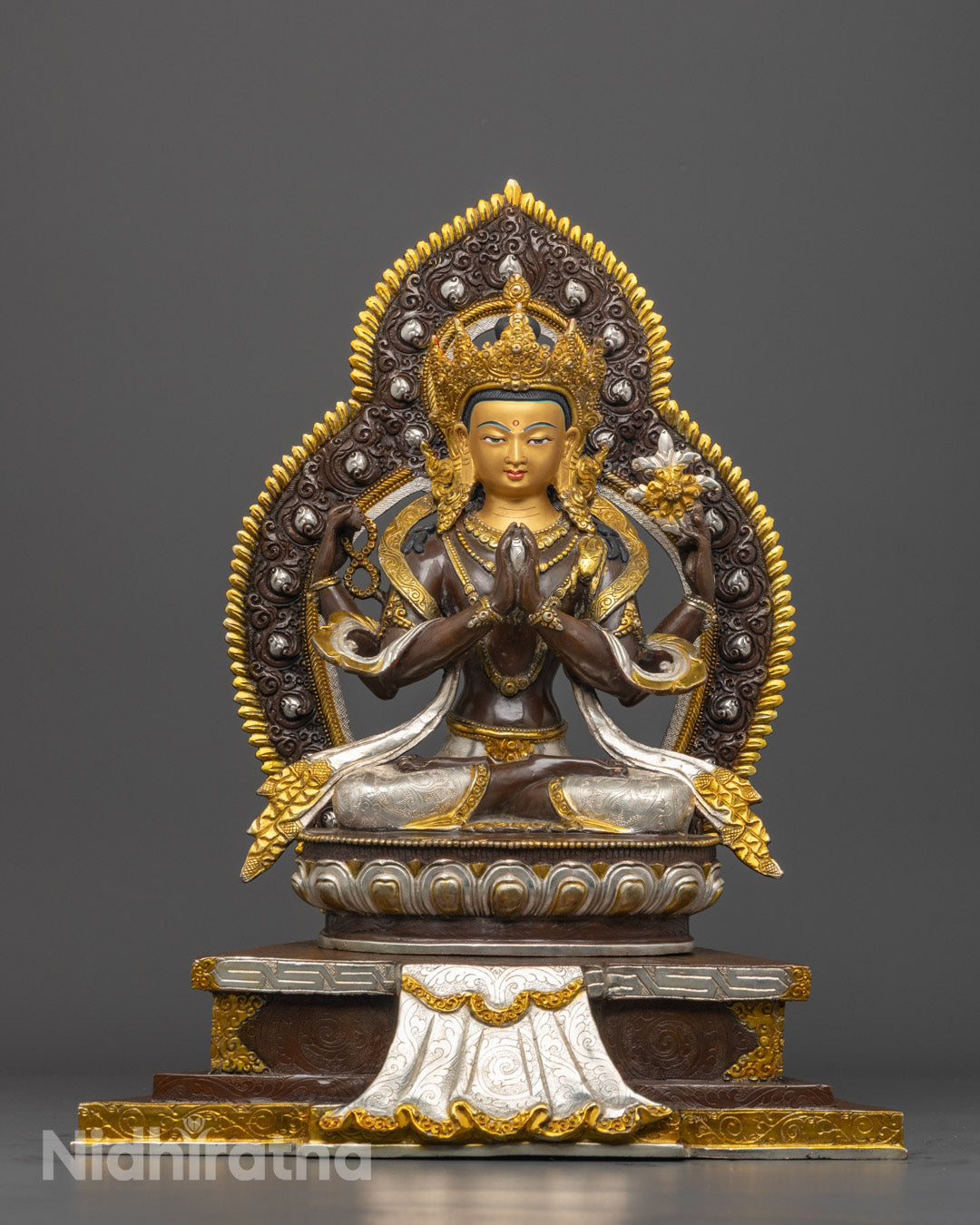 Front view of hand-carved Chenrezig statue with four arms, seated on a lotus throne