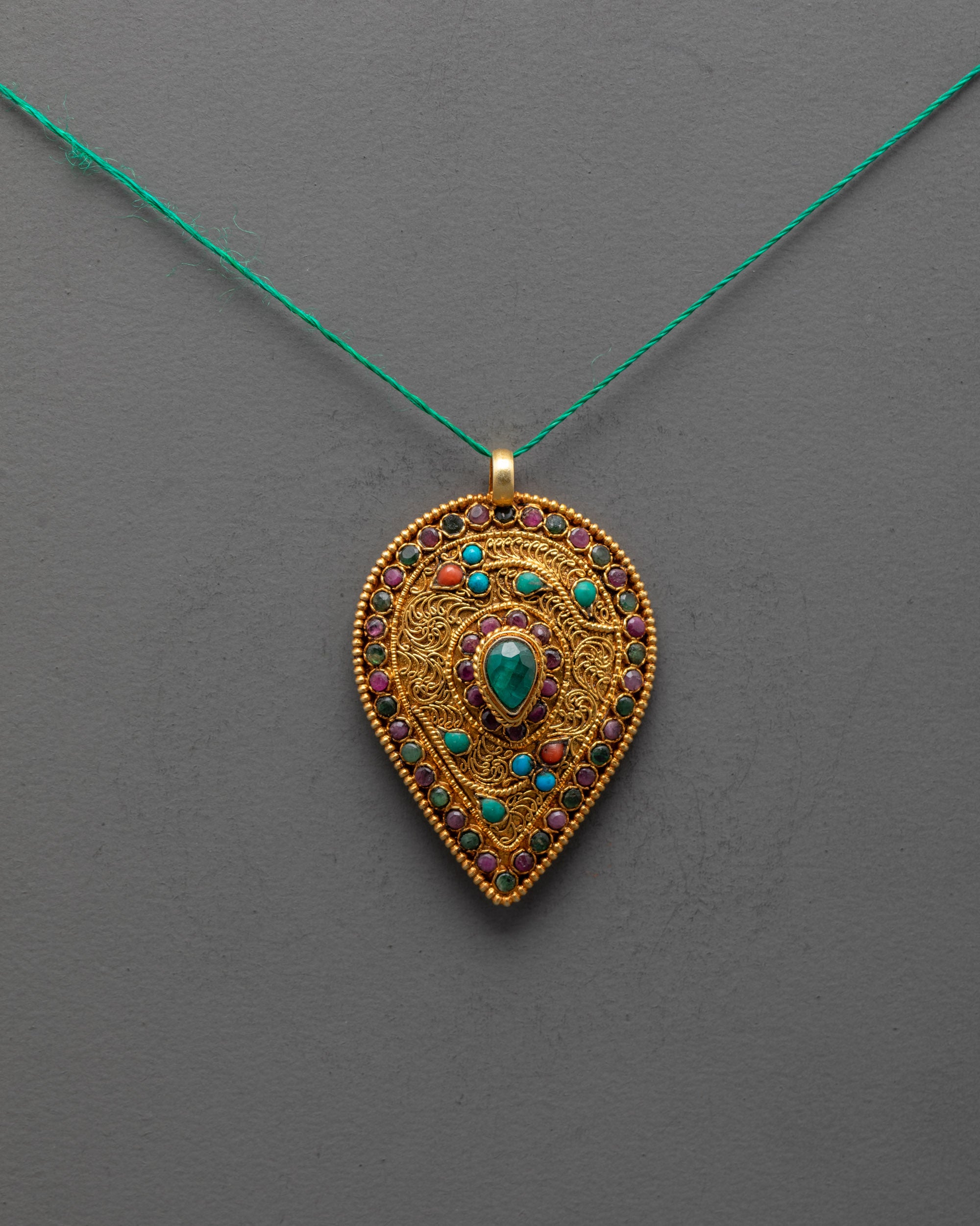 Front view of handmade Tibetan leaf-shaped locket with emerald and semi-precious stones