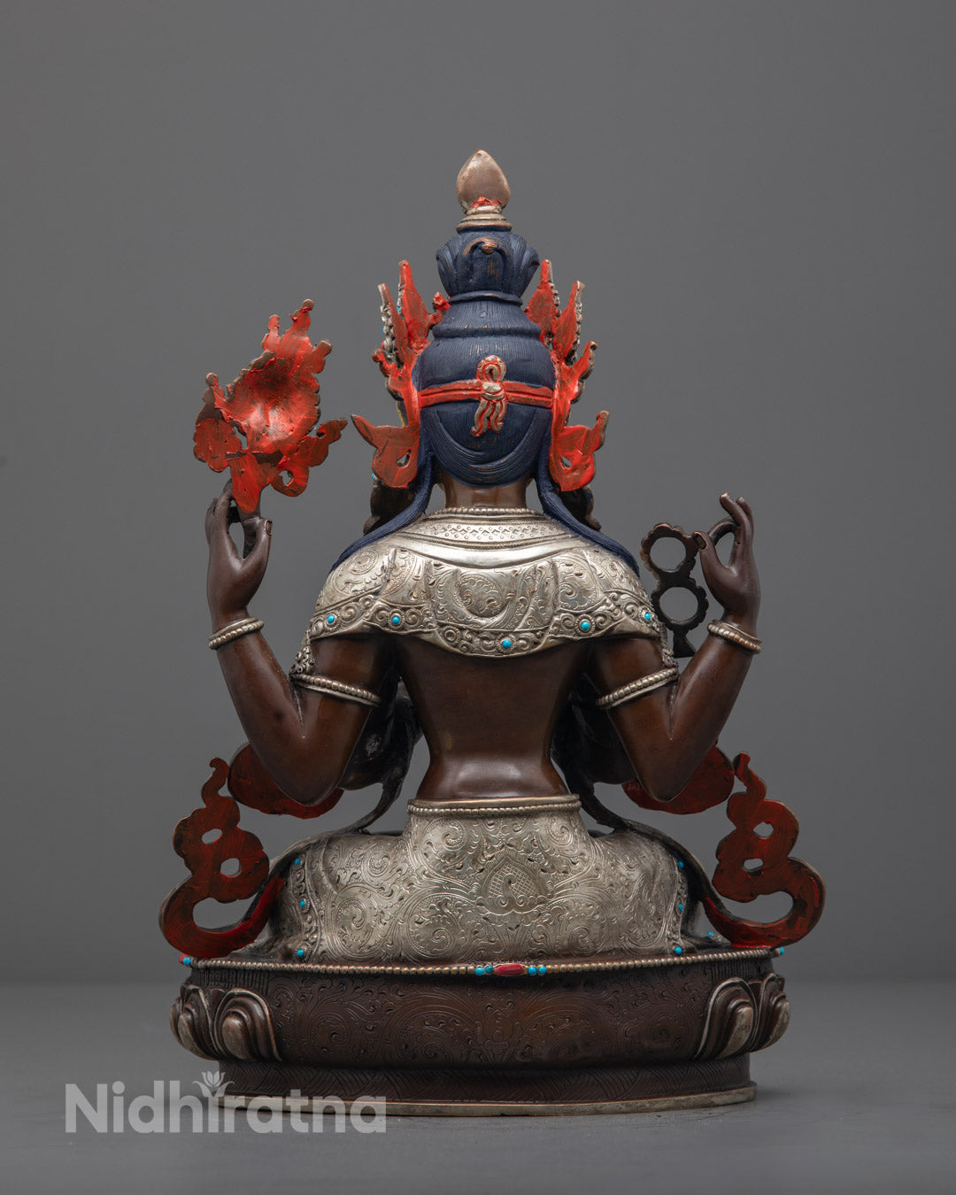 Oxidized Chenrezig statue on lotus base, showcasing silver plating, colorful accents, and sacred iconography from Nepalese craftsmanship."