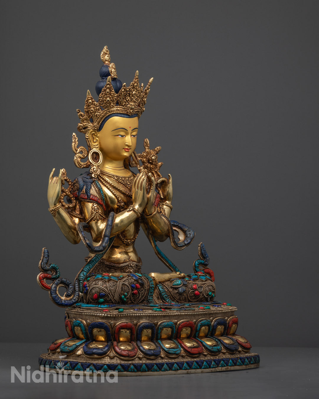 Chenrezig sculpture featuring multiple arms symbolizing compassion, decorated with vibrant semi-precious stones and golden accents.