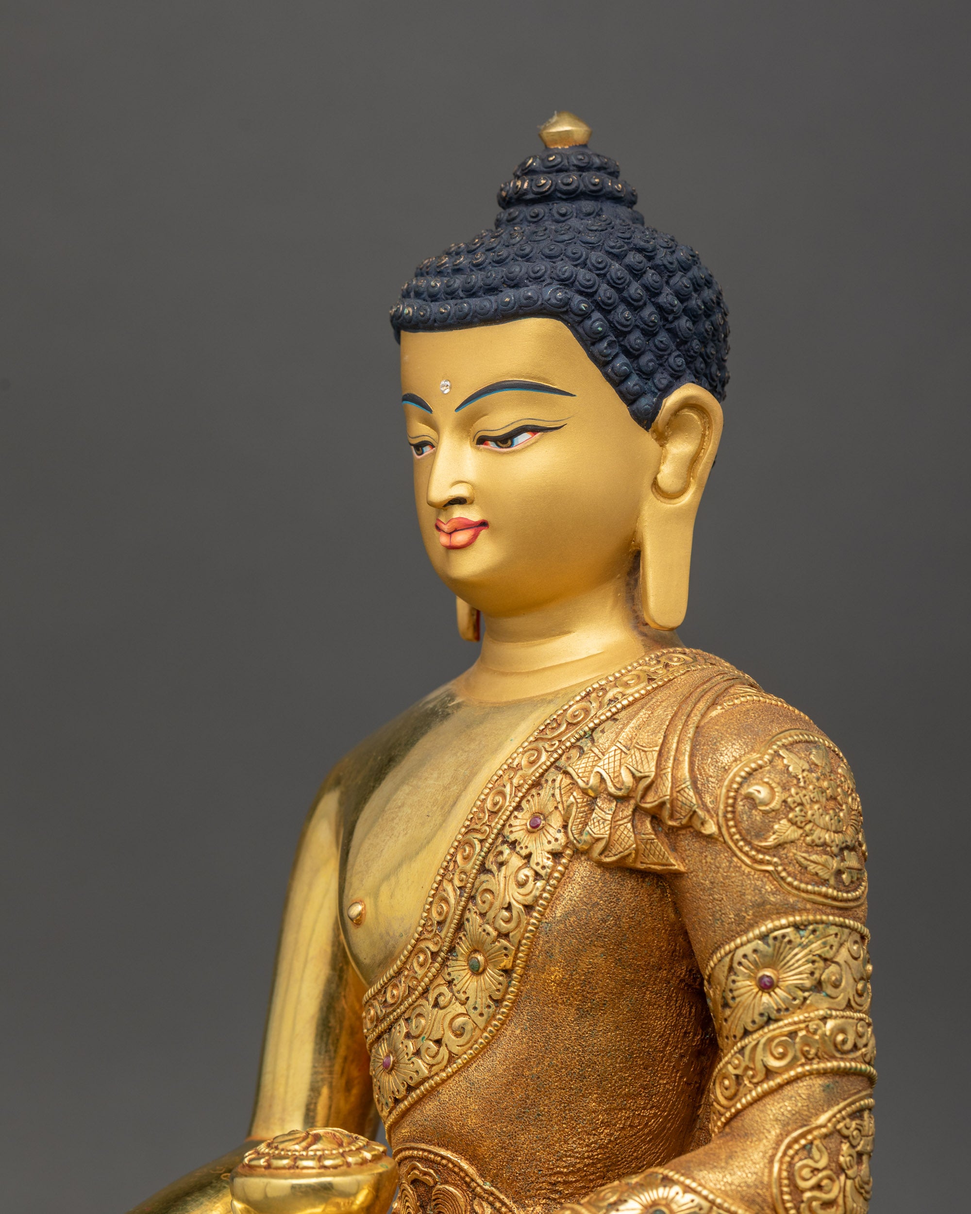 Gold-gilded Shakyamuni Buddha statue with serene expression and flowing monastic robes