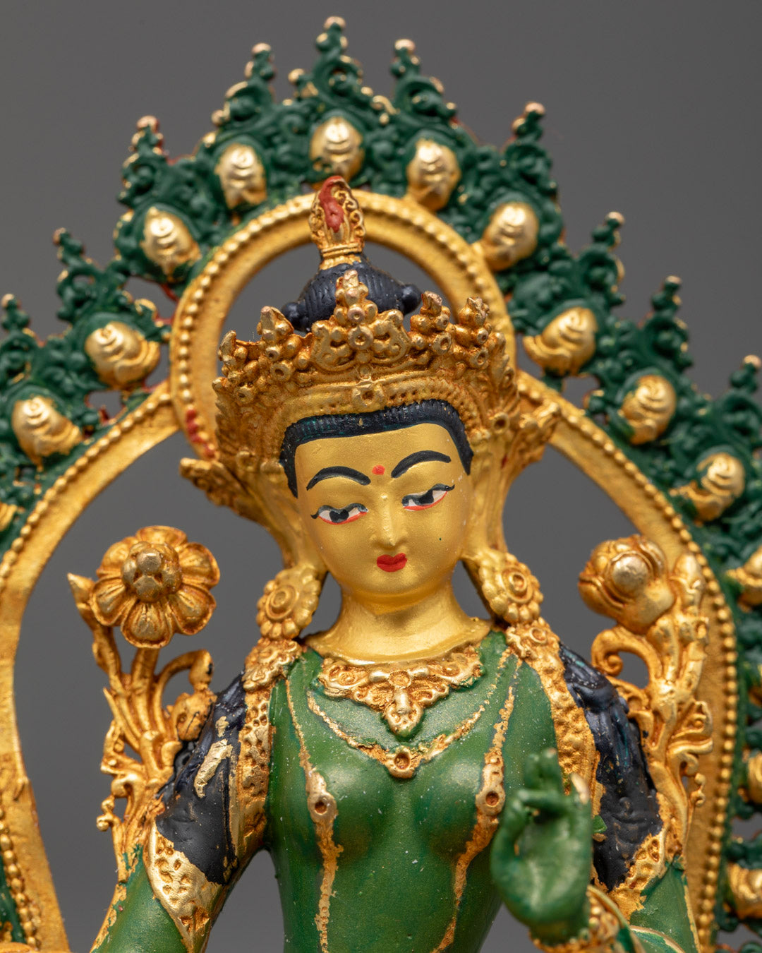 Detailed carving of jewelry crown robe and Uptala flowers on green Tara Buddhist statue with green halo