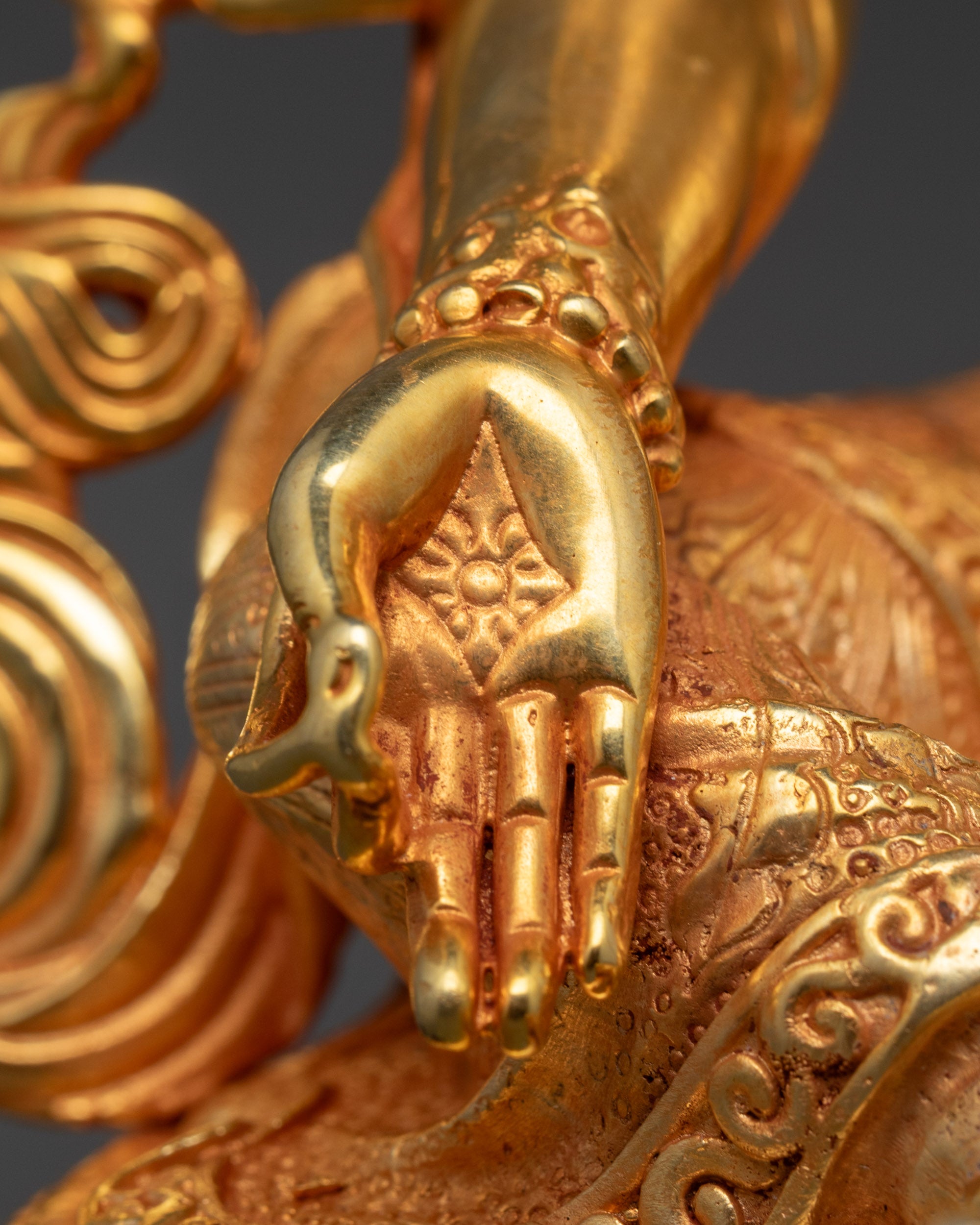 Close-up of a gold statue with detailed hand and bodywork against a dark background