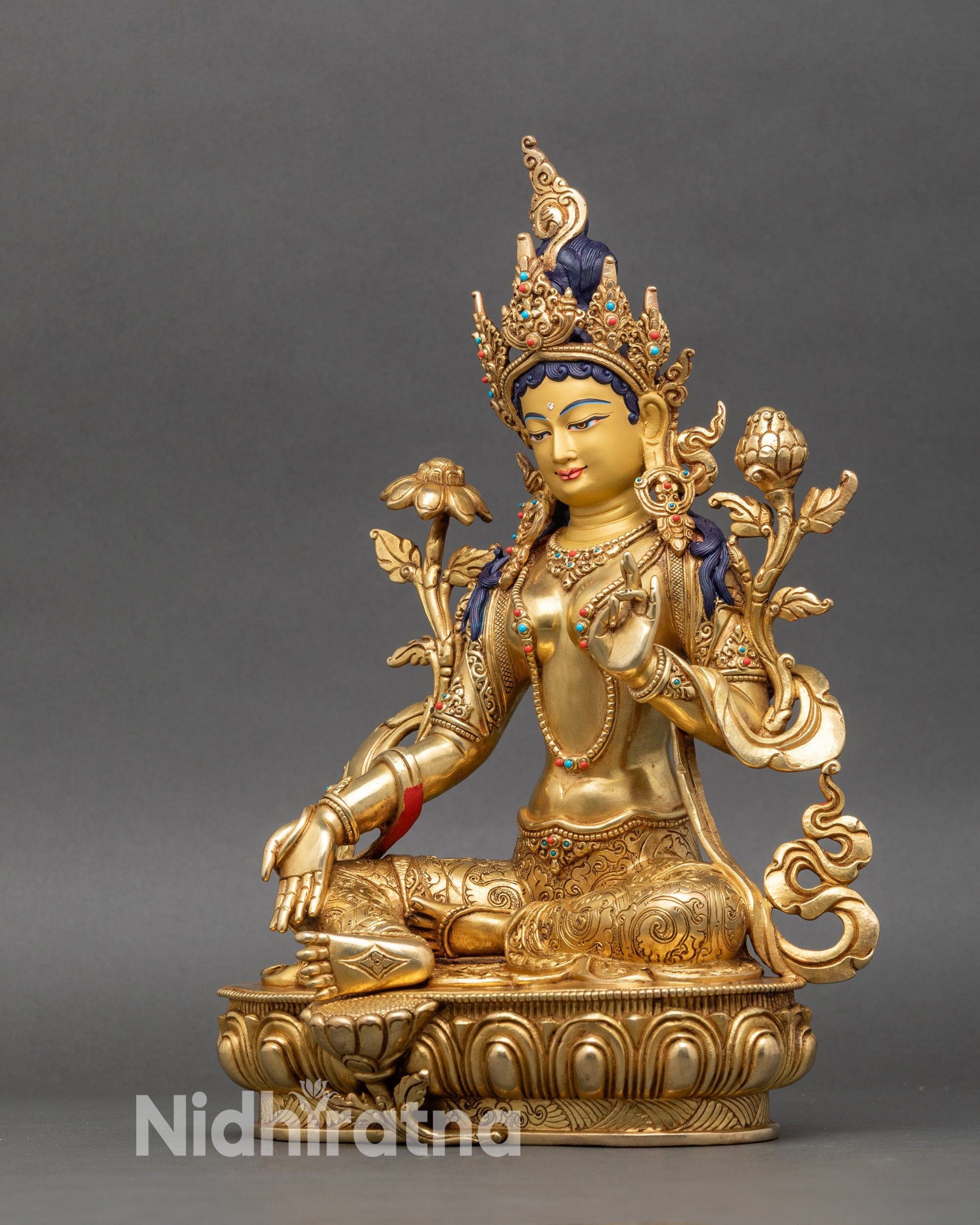 Green Tara deity statue left side showing folded left leg, raised left arm, and decorative details