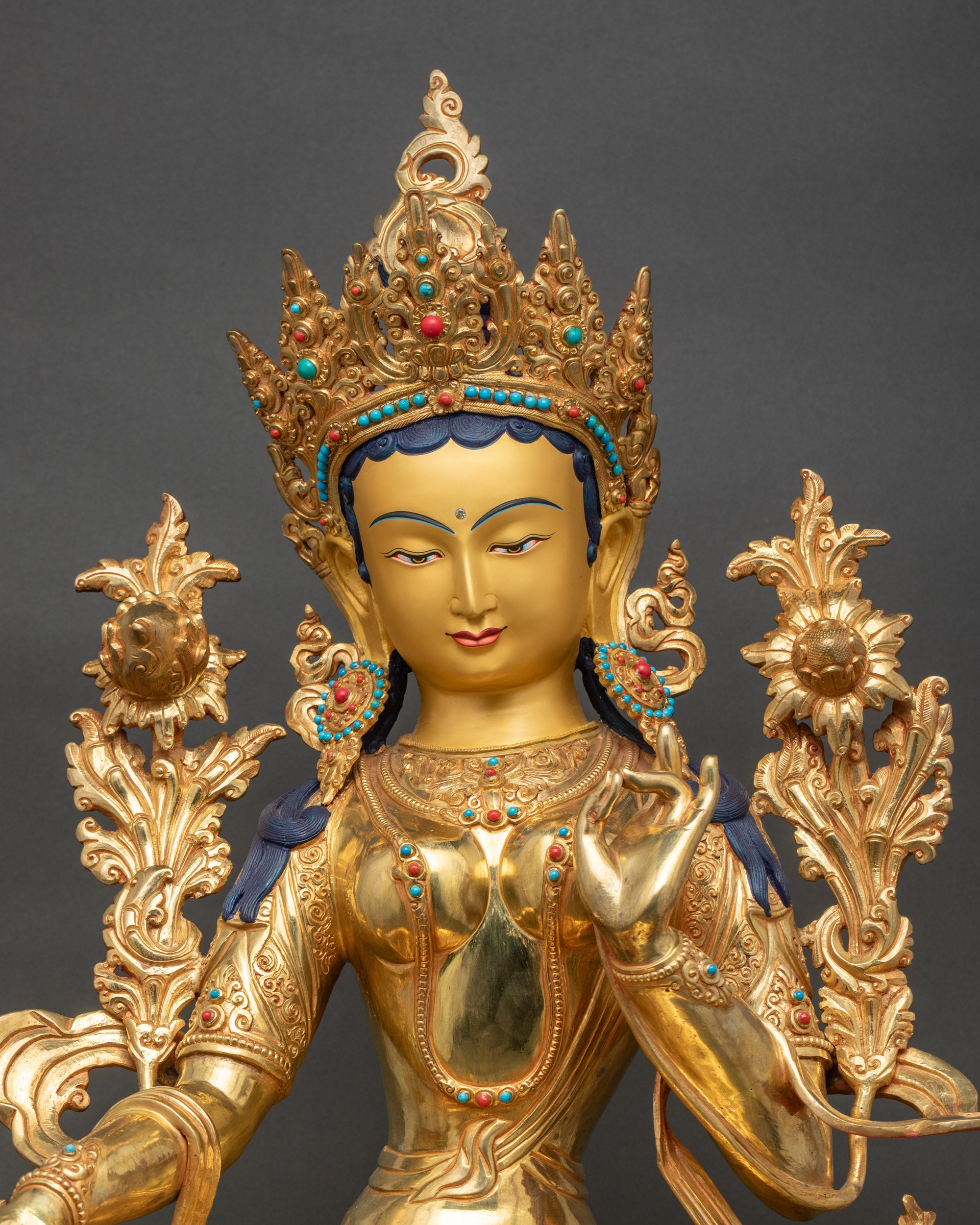 Green Tara statue close up showing crown jewels and gold painted details
