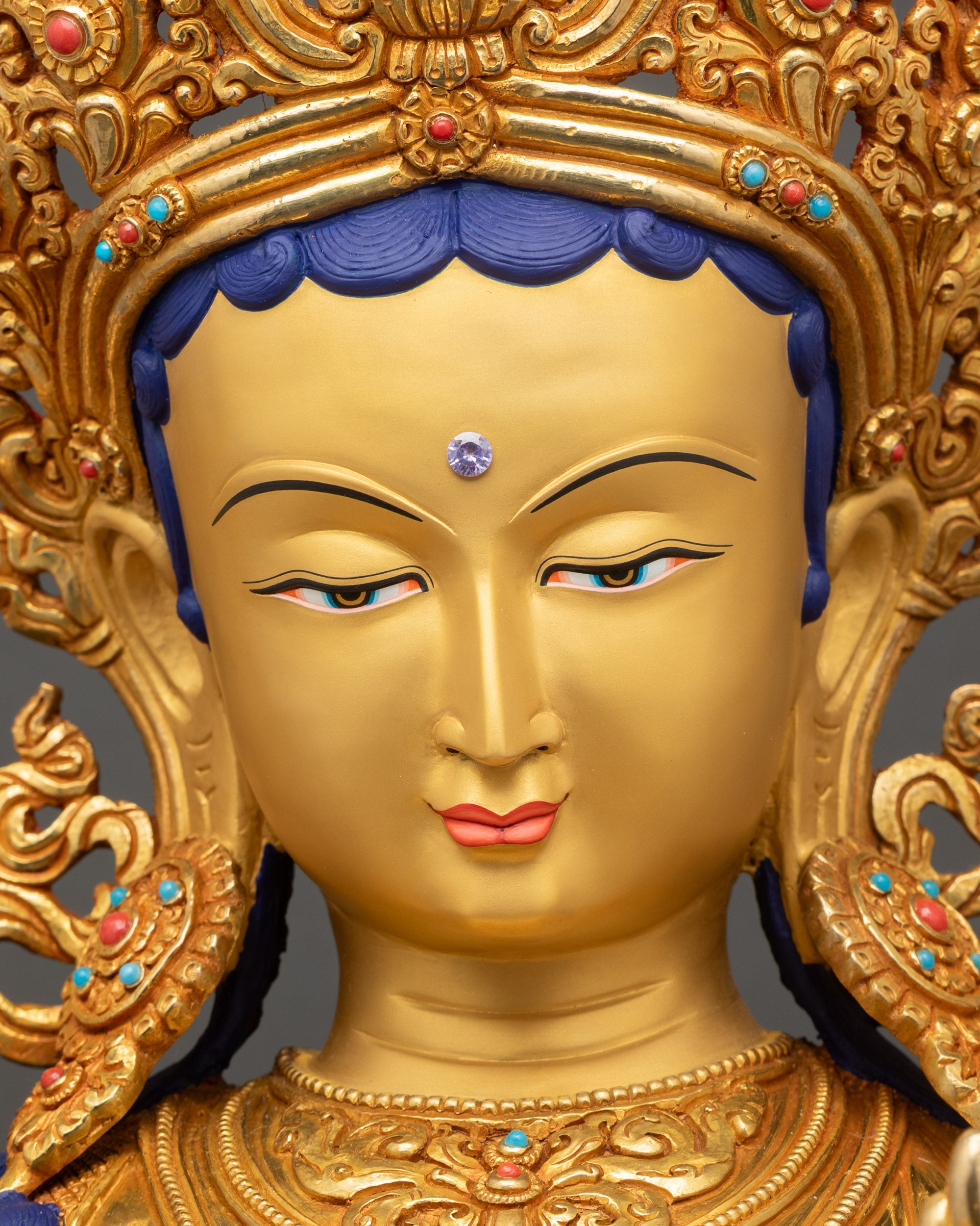 Green Tara statue face close up with gold painted expression and serene gaze