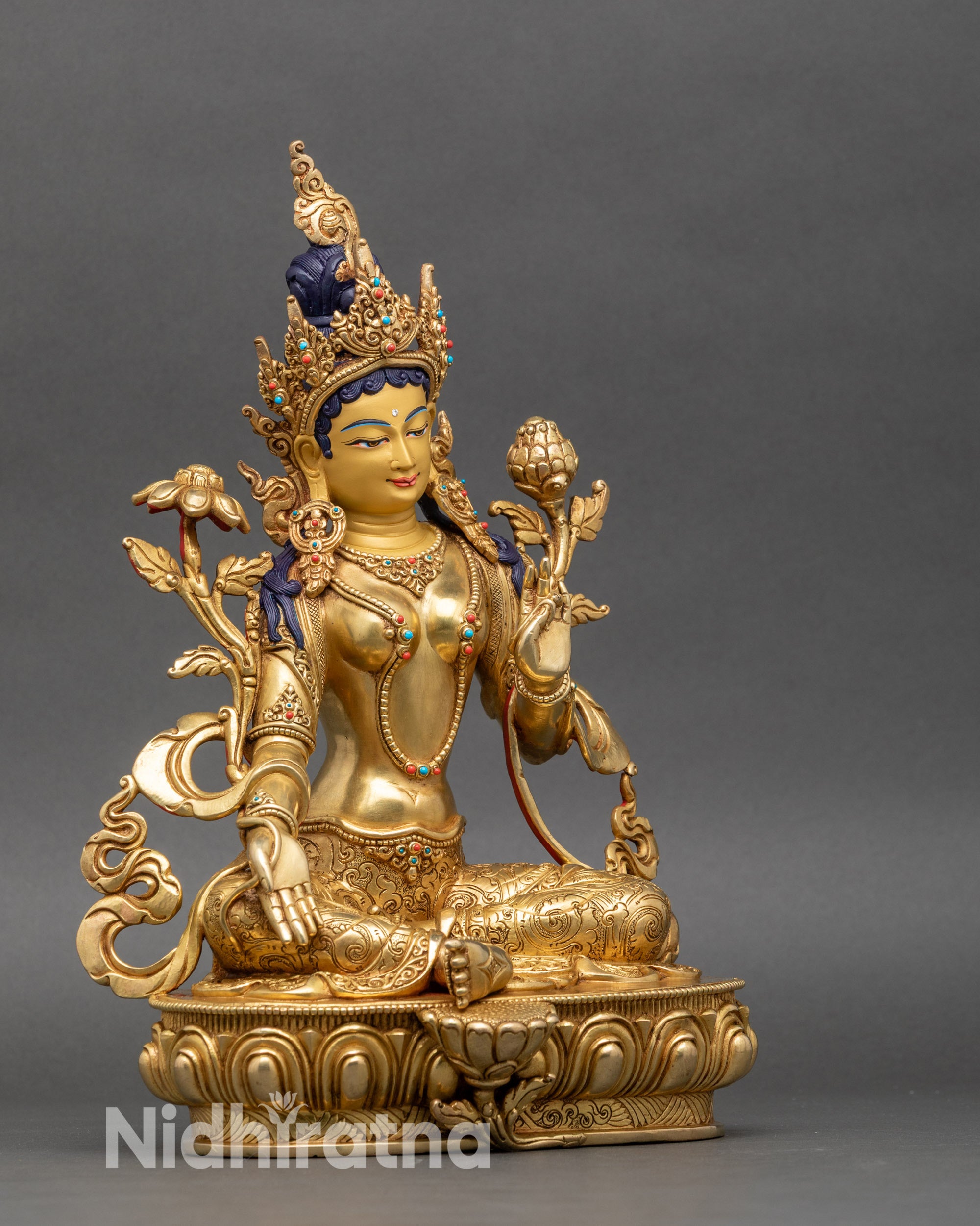 Green Tara statue right side showing extended right leg, raised right arm, and gold fire-gilding