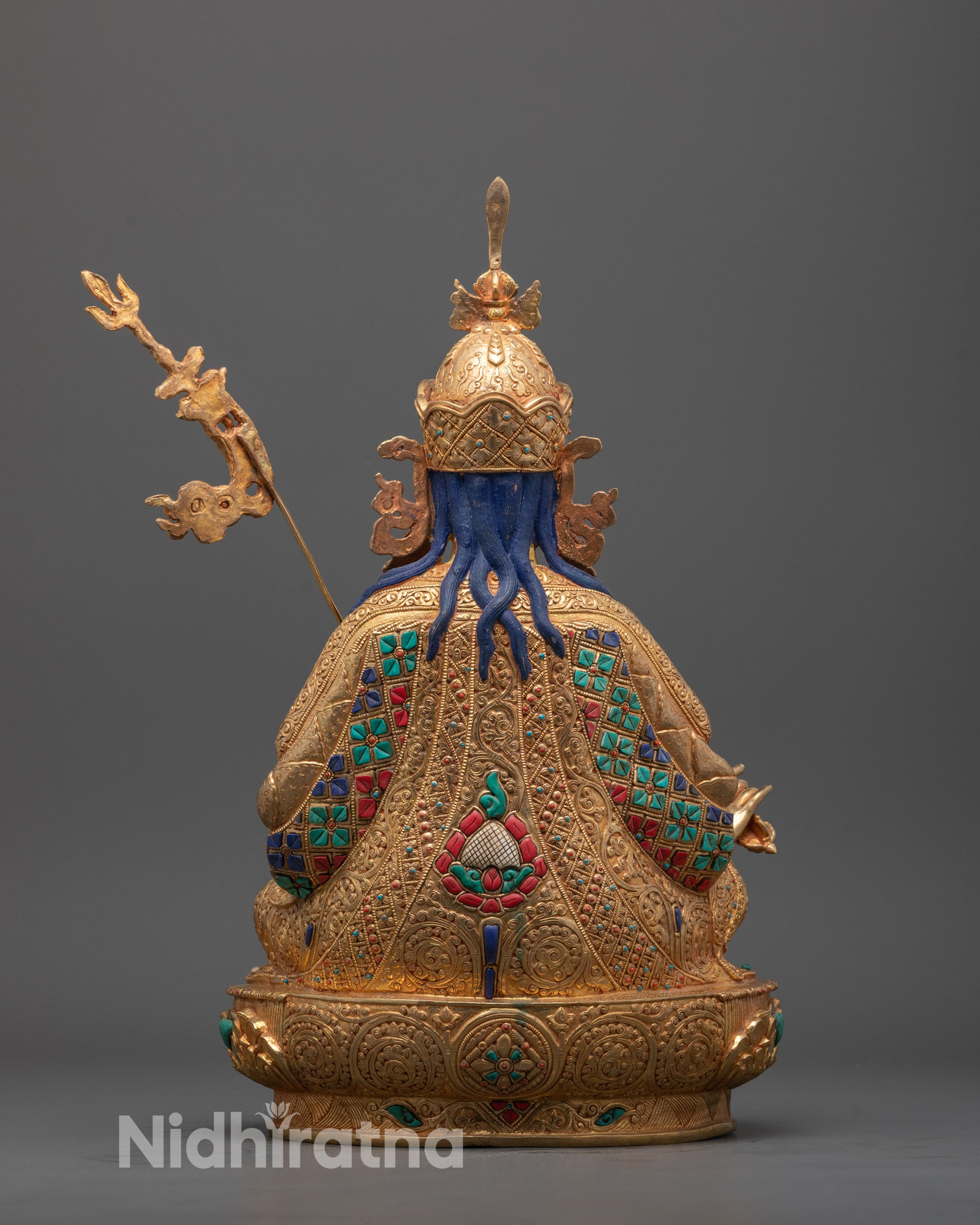 Decorative golden object with intricate designs and blue accents on a gray background