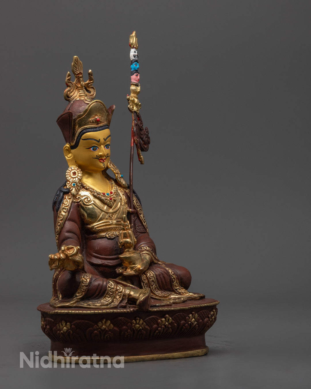 Detailed carving of Padmasambhava statue's crown and jewelry with vibrant colors – traditional lost wax method Buddhist sculpture