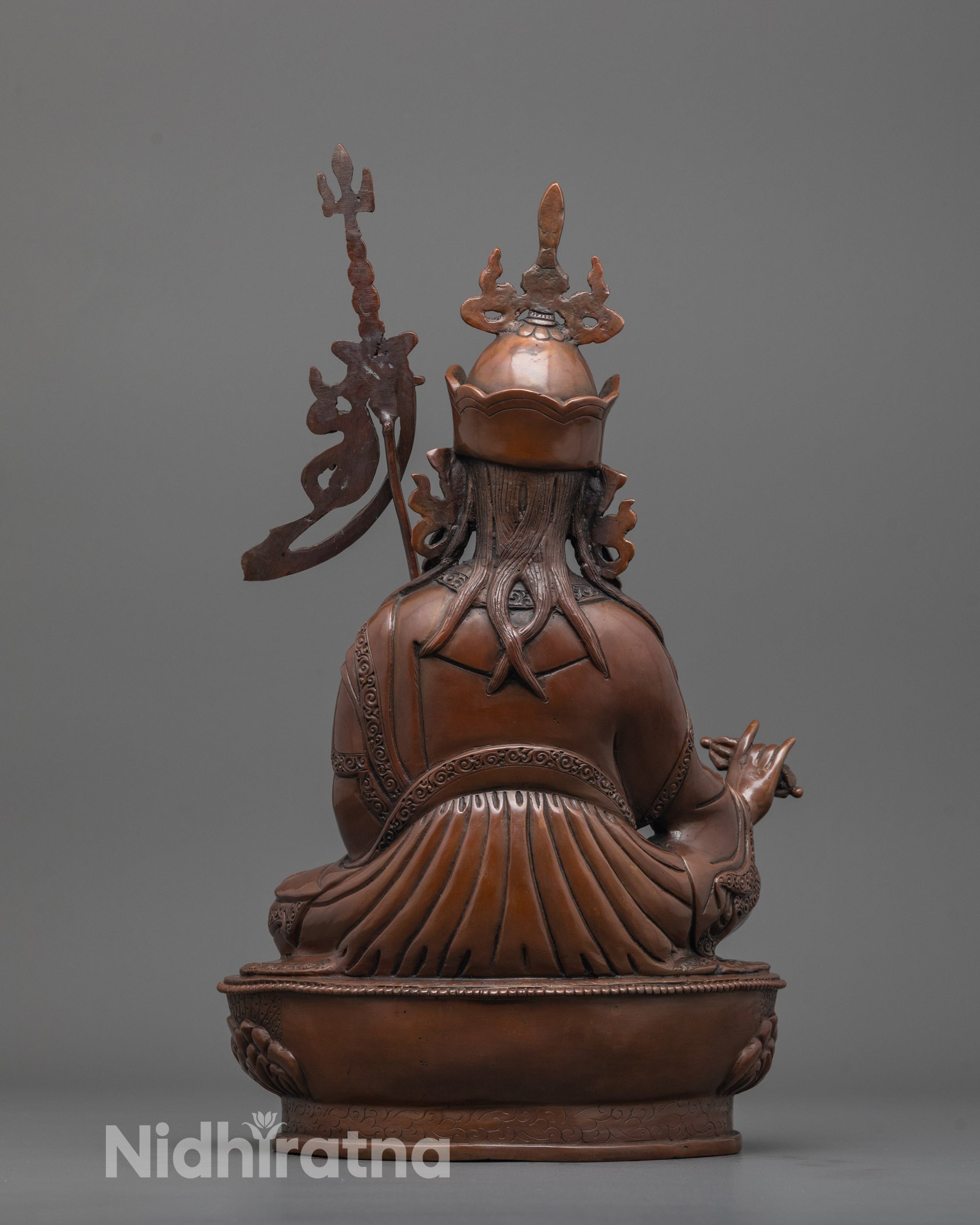 back view of oxidized copper guru rinpoche statue seated on throne with detailed robe