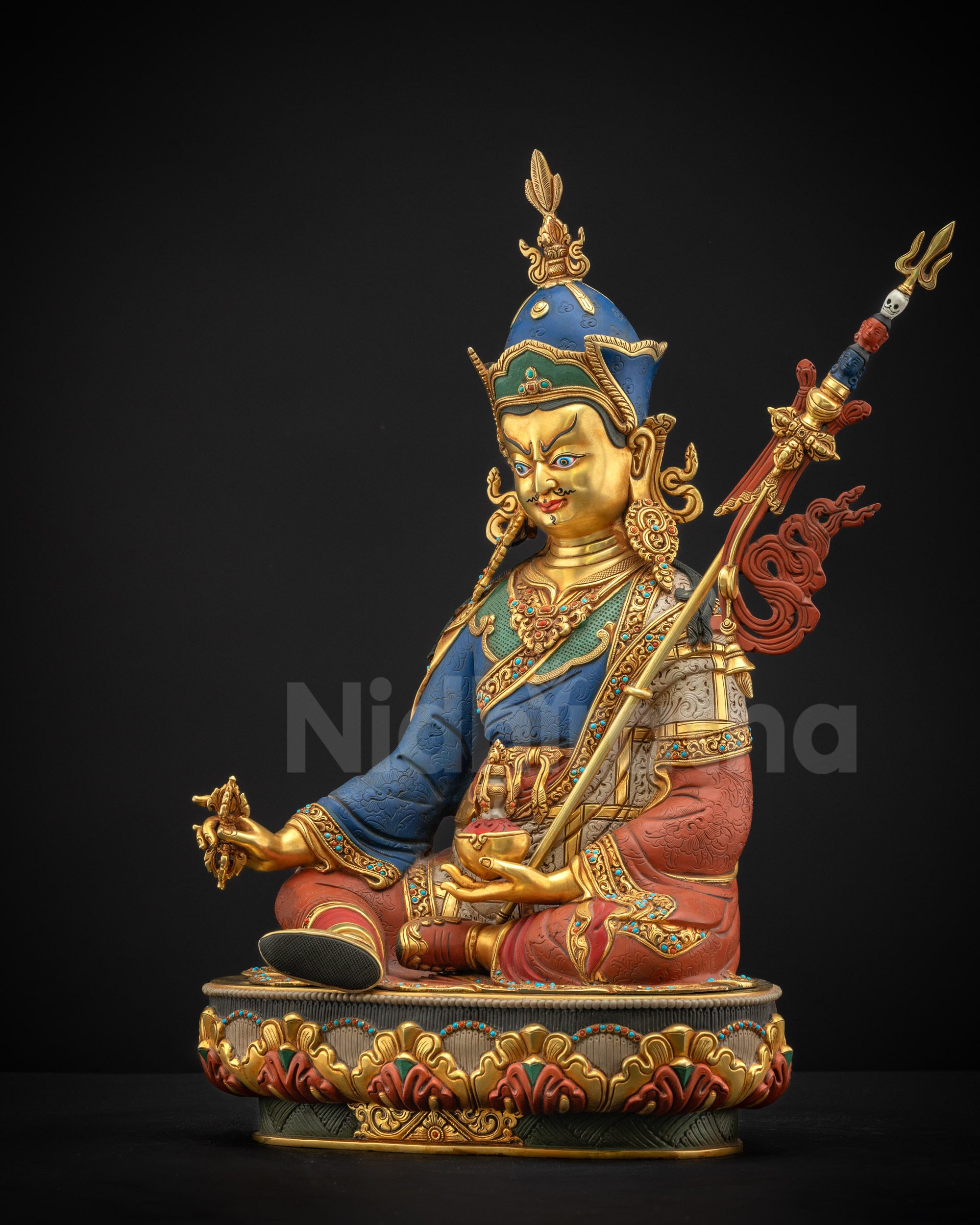 Left profile of Guru Rinpoche statue, detailed robe, lotus pedestal, and gold fire-gilding.