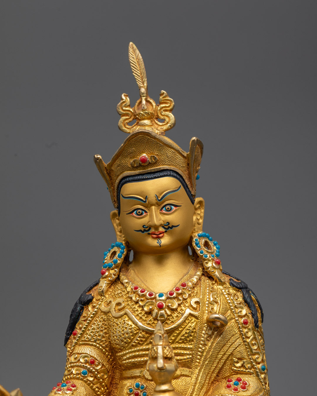 Guru Rinpoche holding a vajra symbolizing compassion, a vase of amrita representing immortality, and three stacked kapalas symbolizing transformation.