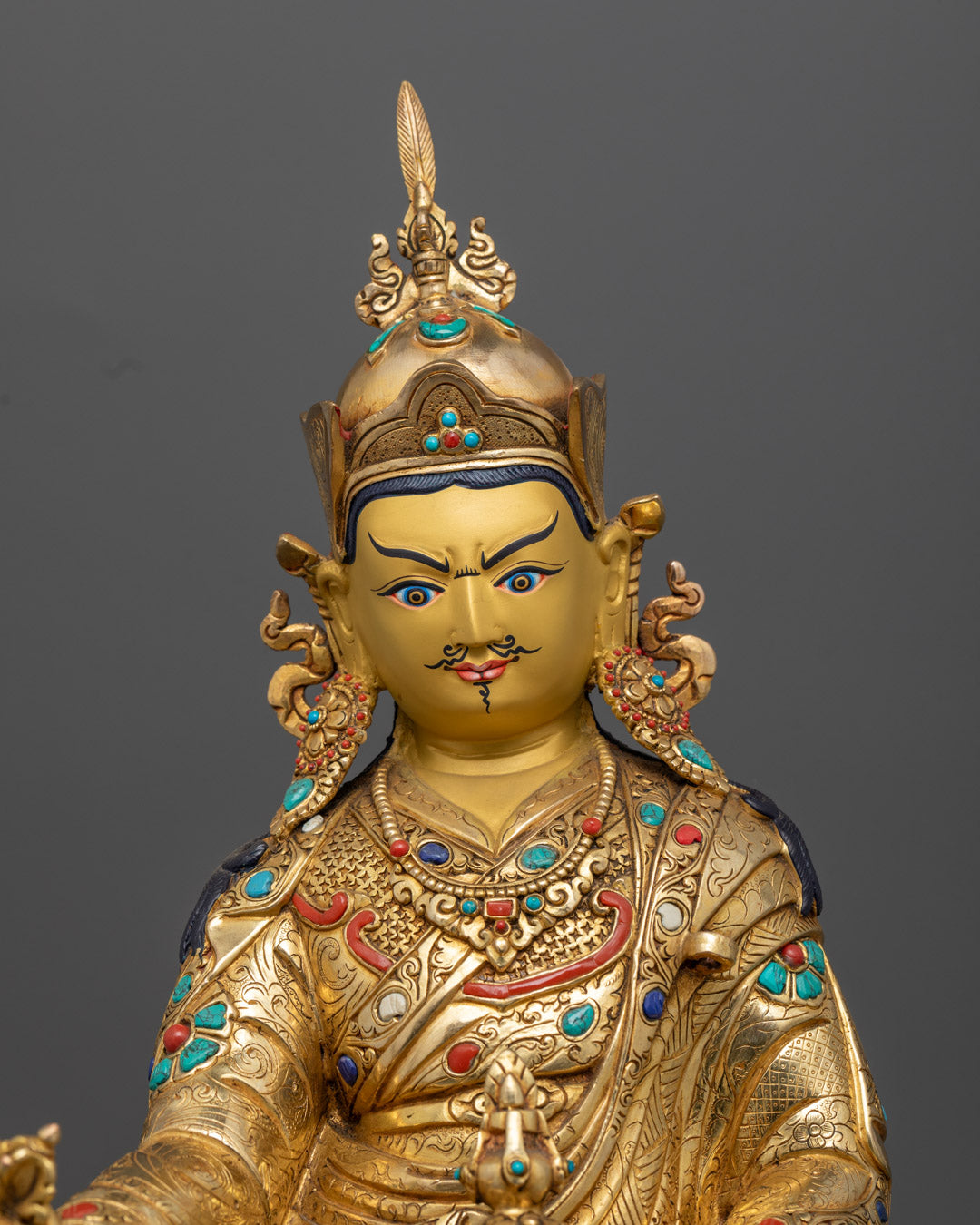 Guru Rinpoche’s serene facial expression and ornate crown, highlighting the intricate craftsmanship and traditional detail.