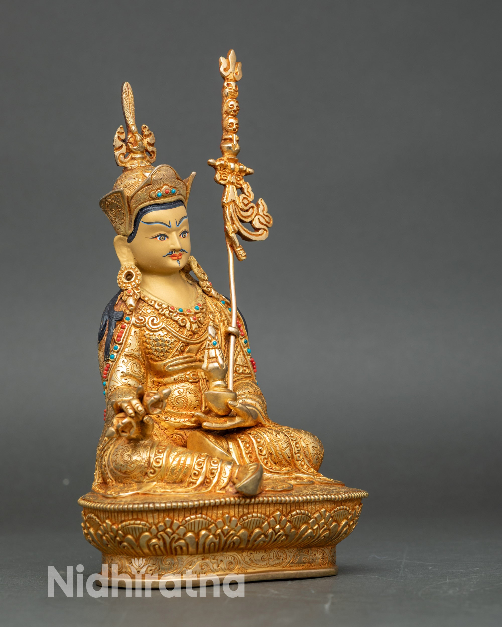 Guru Rinpoche sculpture side view, holding vajra and khatvanga, handcrafted in Nepalese copper with gold finish for meditation altars.
