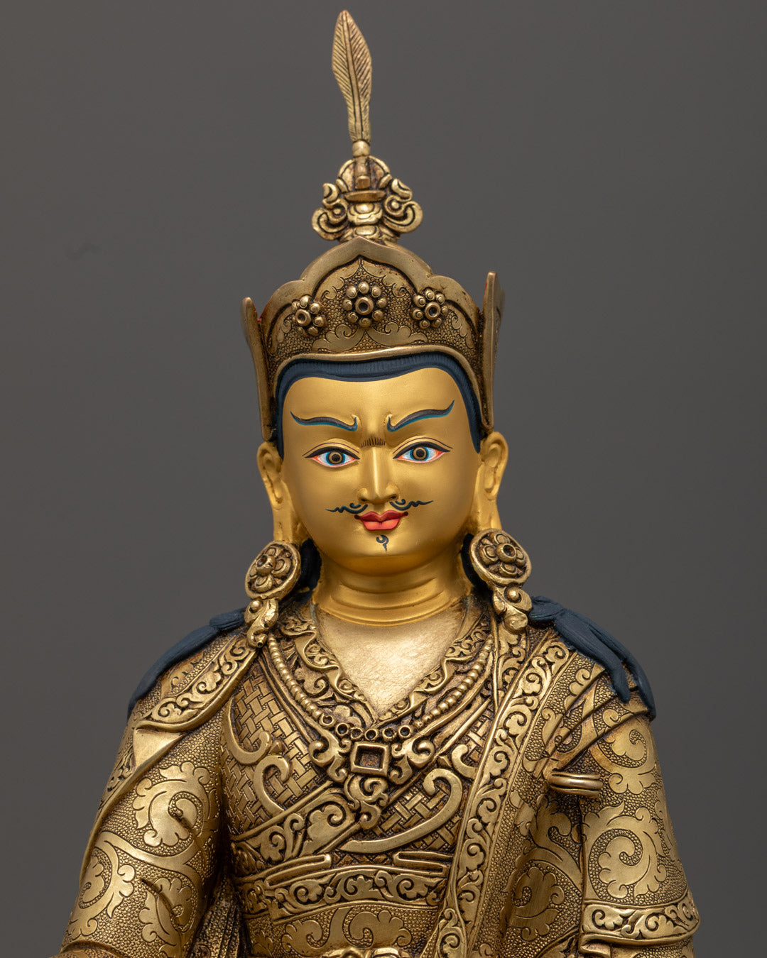 Guru Rinpoche statue's serene gold-plated face and hand-painted body, symbolizing wisdom and compassion.