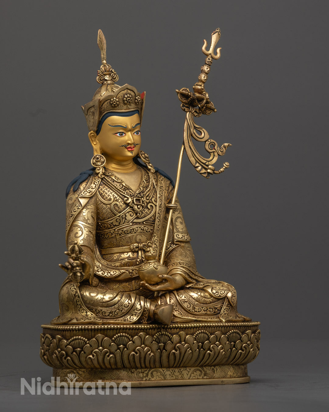 Guru Rinpoche sculpture with intricate carvings, colorful acrylic accents, and radiant gold finish.