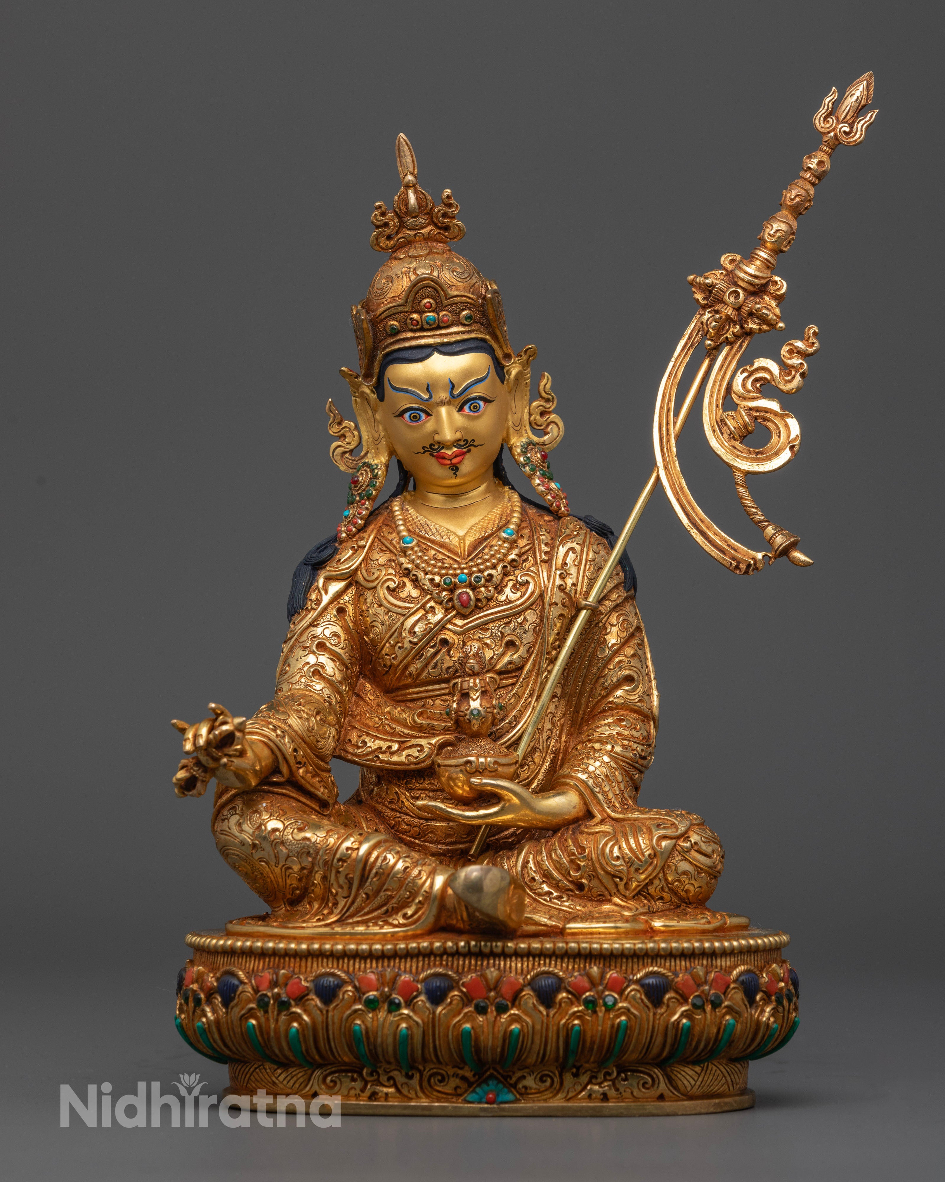 Handcrafted Guru Rinpoche statue seated on a lotus and moon disc, featuring a regal expression with mustache and goatee, adorned with gold jewelry and semi-precious stones.