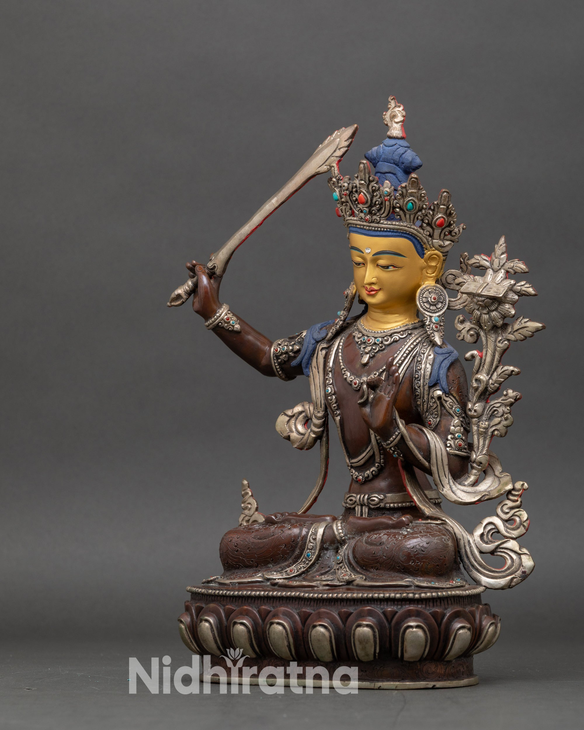 Left profile of Manjushri statue highlighting sword, flower, and oxidized copper finish