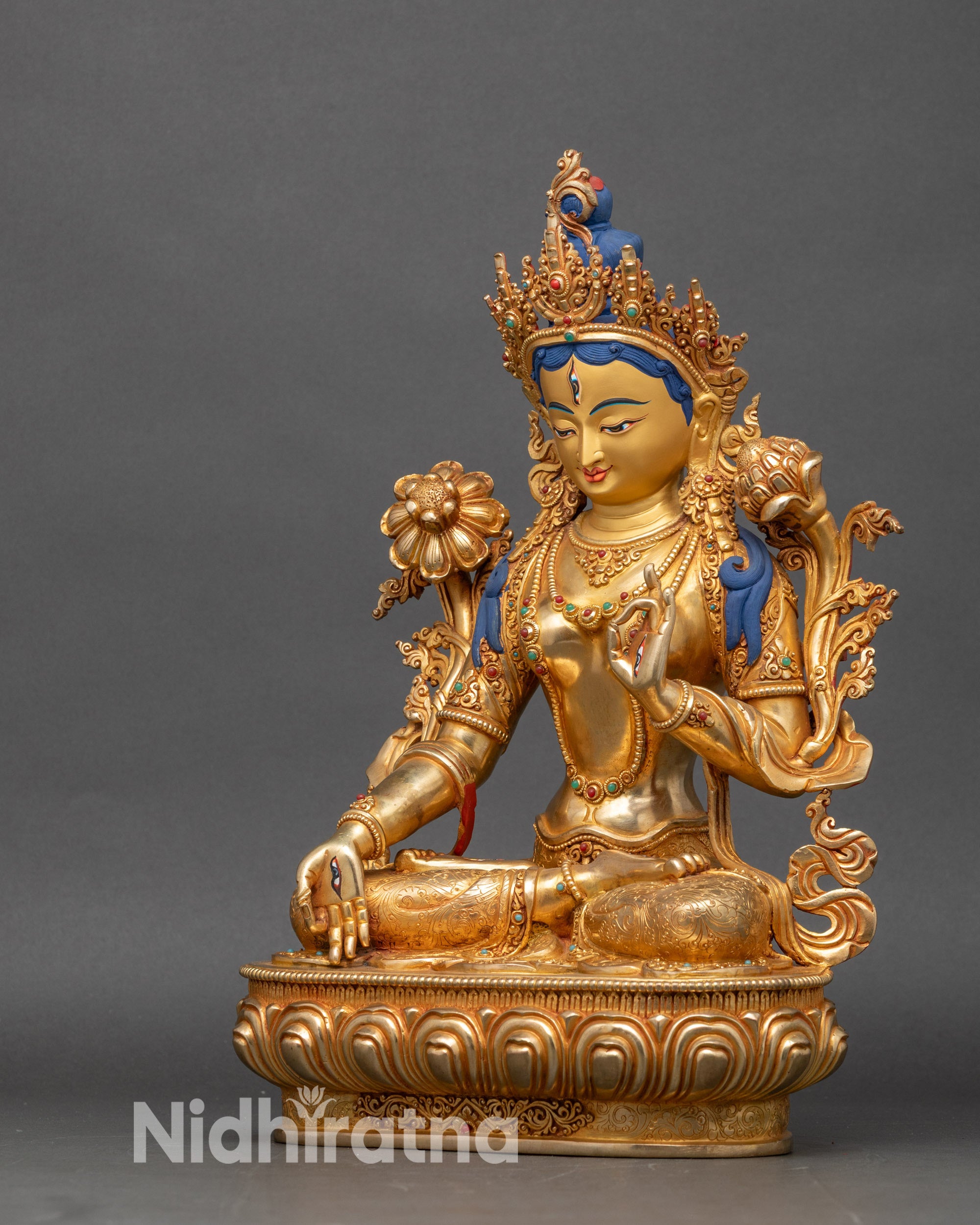 Left profile of White Tara statue, seated on lotus throne, gold fire-gilded copper