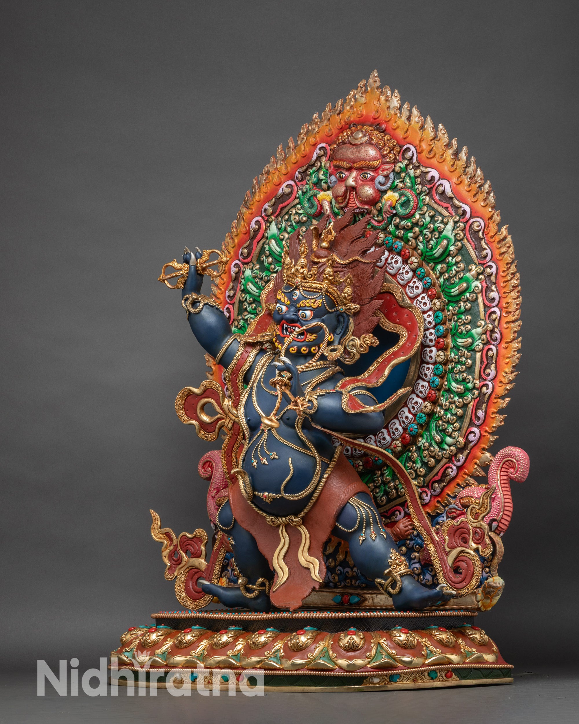 Left profile of large Vajrapani statue with detailed ornaments, semi-precious stones, and halo