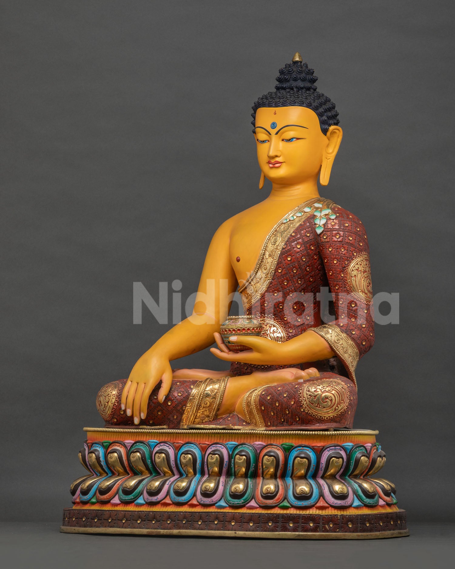 Left side view of colorful Shakyamuni Buddha statue, alms bowl in hand