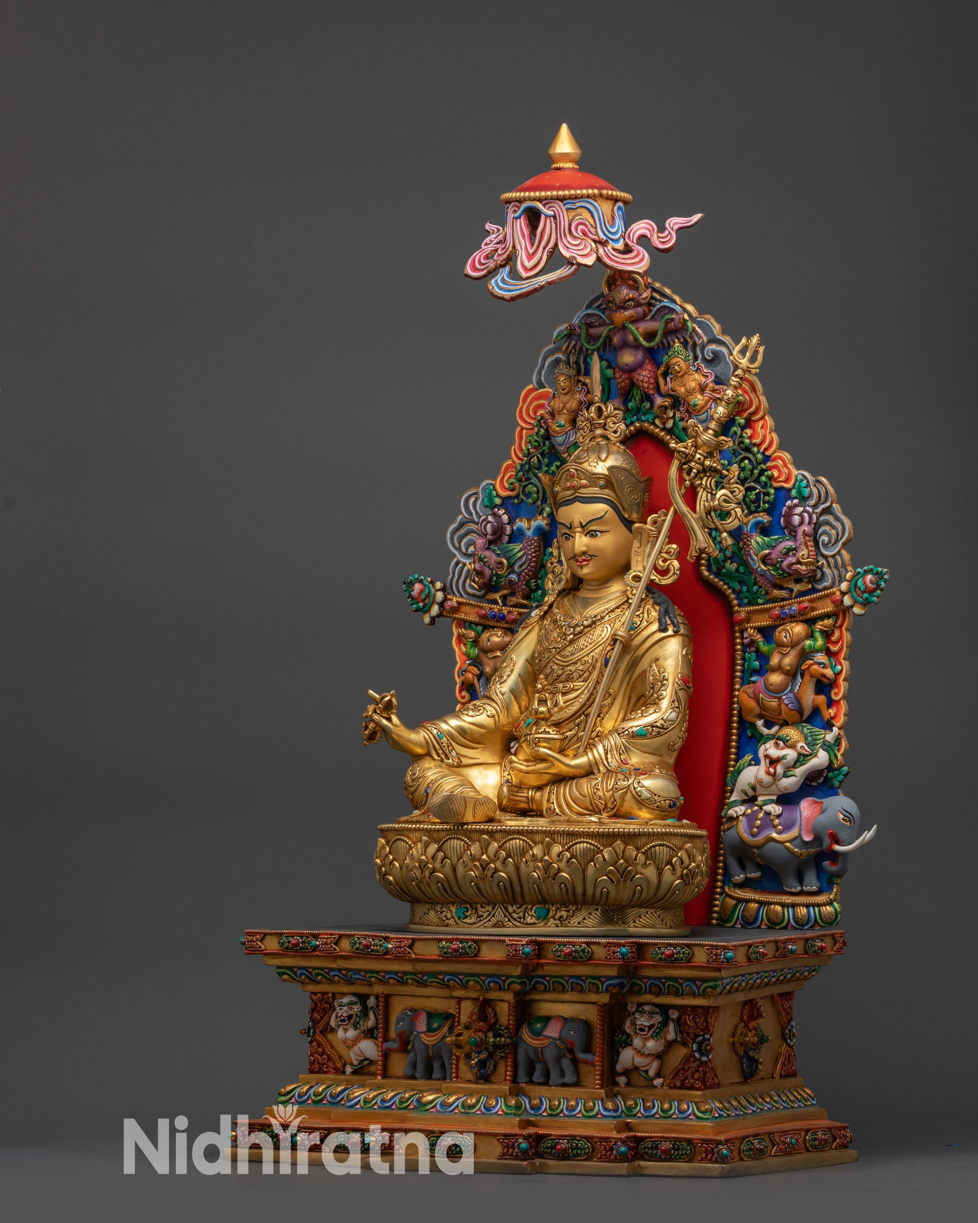 Left view side of Guru Rinpoche statue with disciples Yeshe Tsogyal and Mandarva on throne