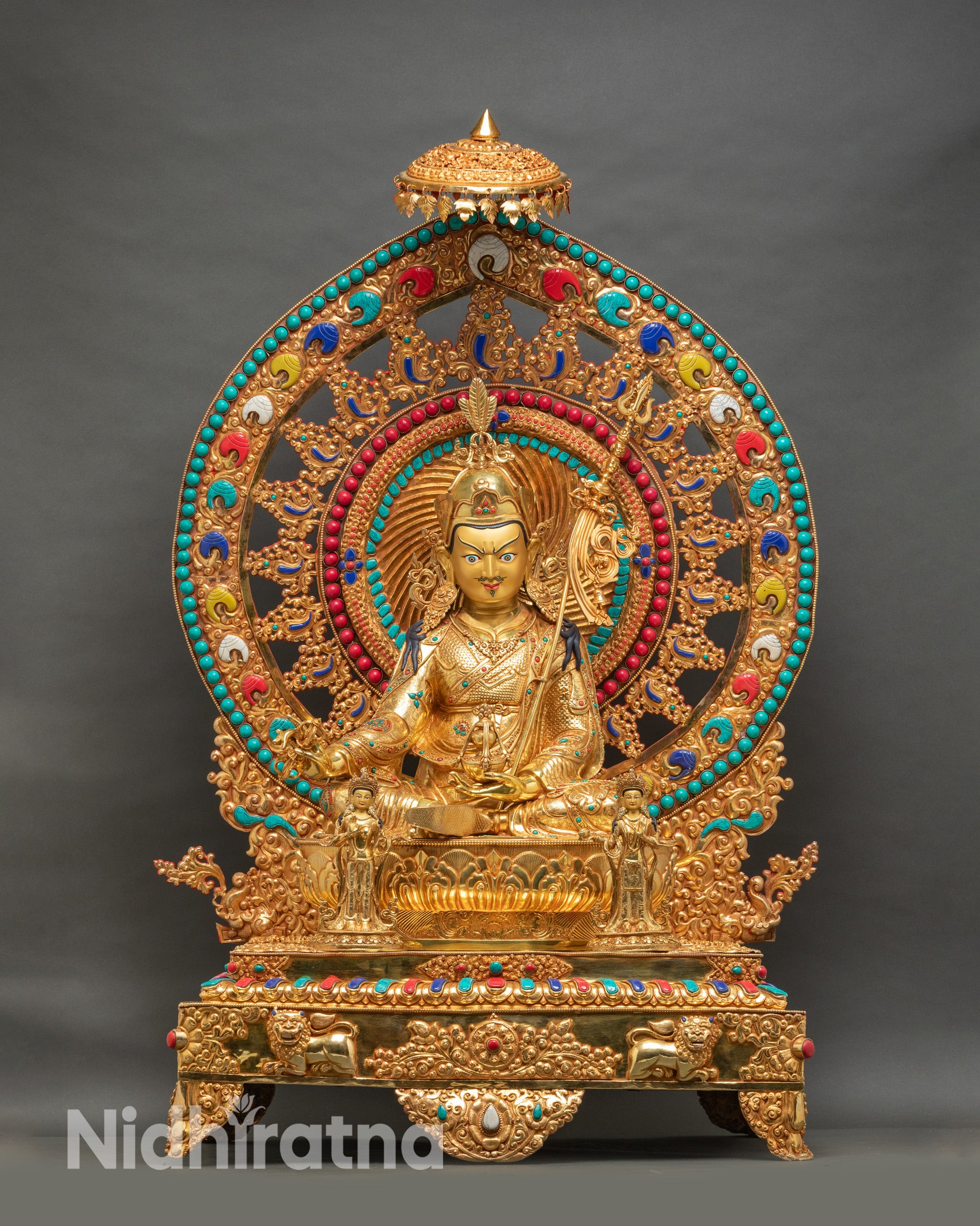 Life-size Guru Rinpoche statue facing forward with ornate golden throne, lotus pedestal, and turquoise inlaid halo