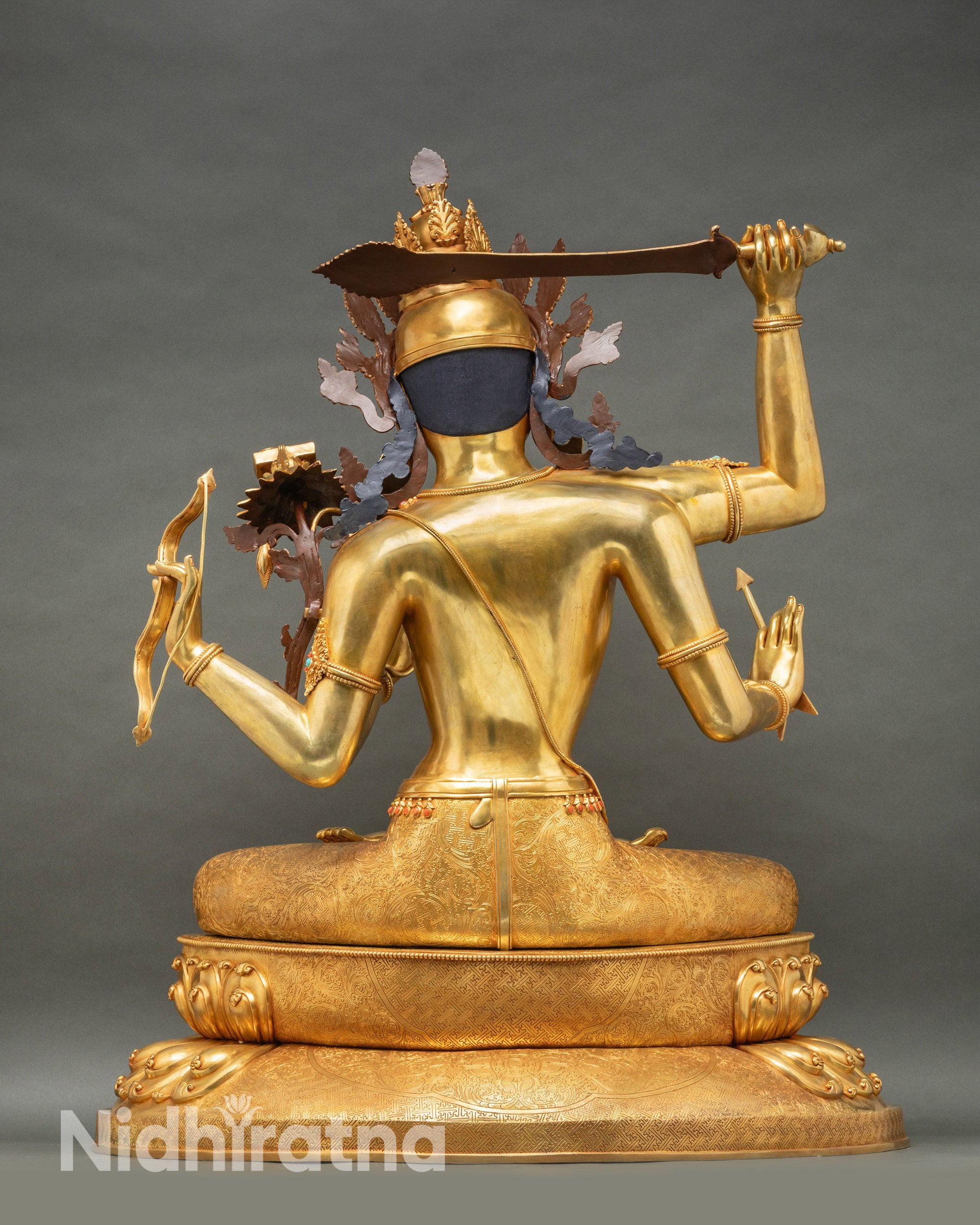 Maha Manjushri statue back view revealing intricate crown detailing, 24K gold fire-gilded surface, and ornamental base