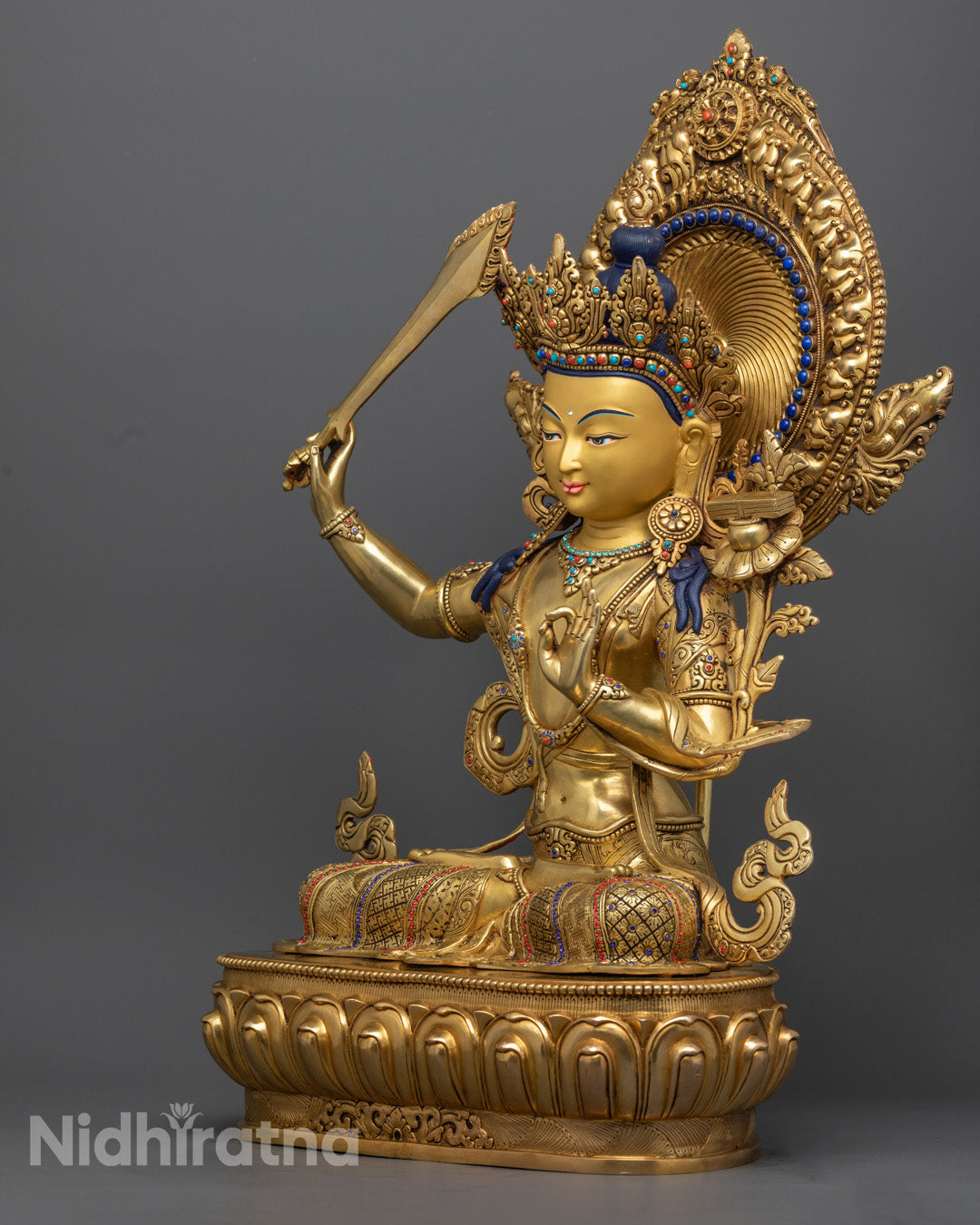 Manjushri Bodhisattva’s serene gold-plated face, adorned with semi-precious stones and traditional Tibetan ornamentation