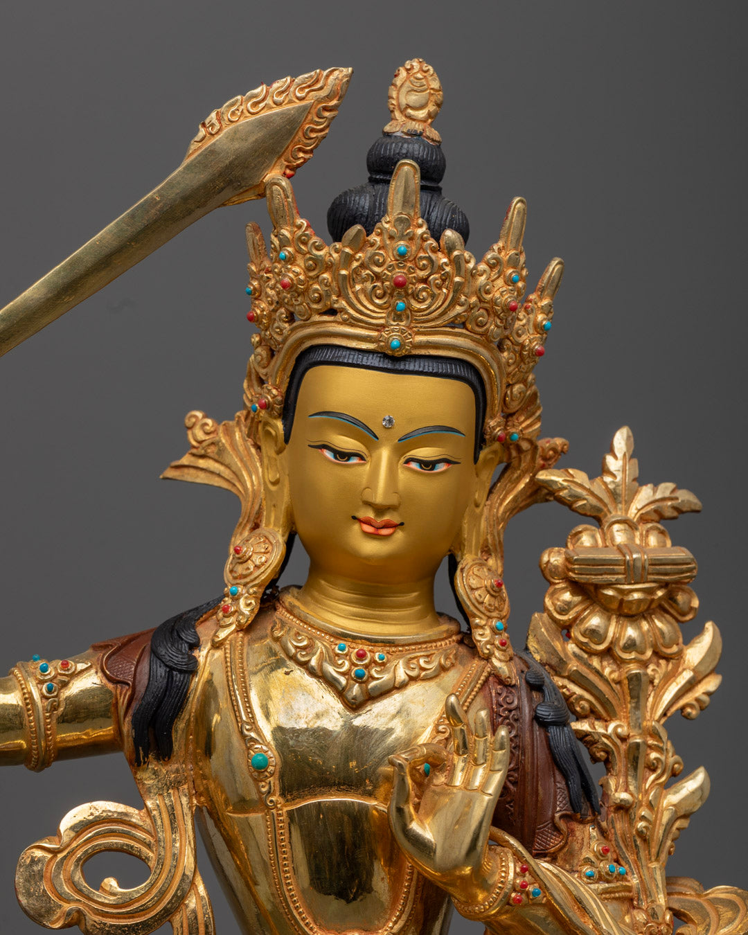 Manjushri statue adorned with rich acrylic colors and semi-precious stones.