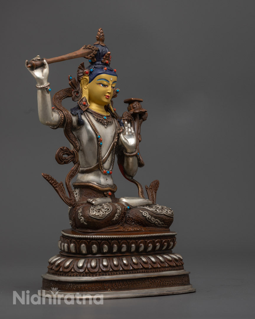 Manjushri statue showing the silver-plated sword of wisdom and intricate gemstone embellishments on the robe and lotus throne.