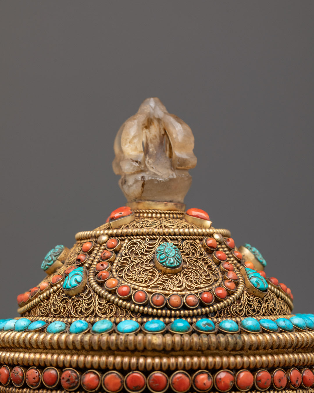 Overhead close-up of copper teapot's crystal finial and gemstone decorations