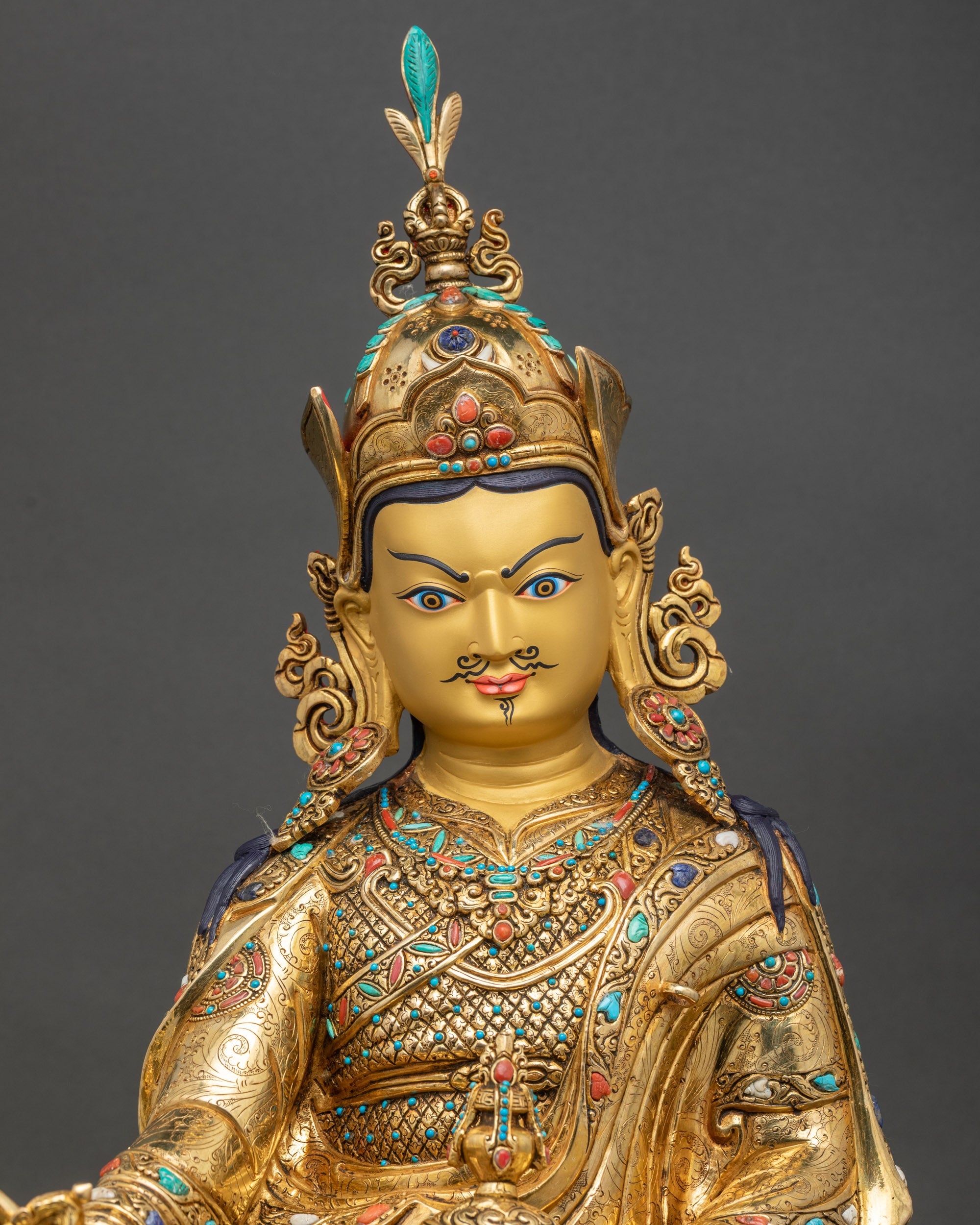 Close-up of Padmasambhava statue showing gold fire-gilding, copper texture, and lotus throne details