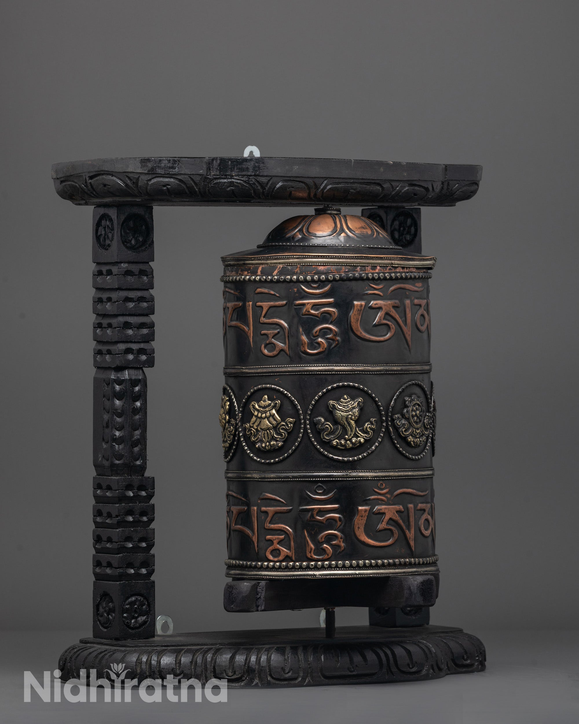 Prayer wheel showcasing bronze auspicious symbols and rich black acrylic paint finish