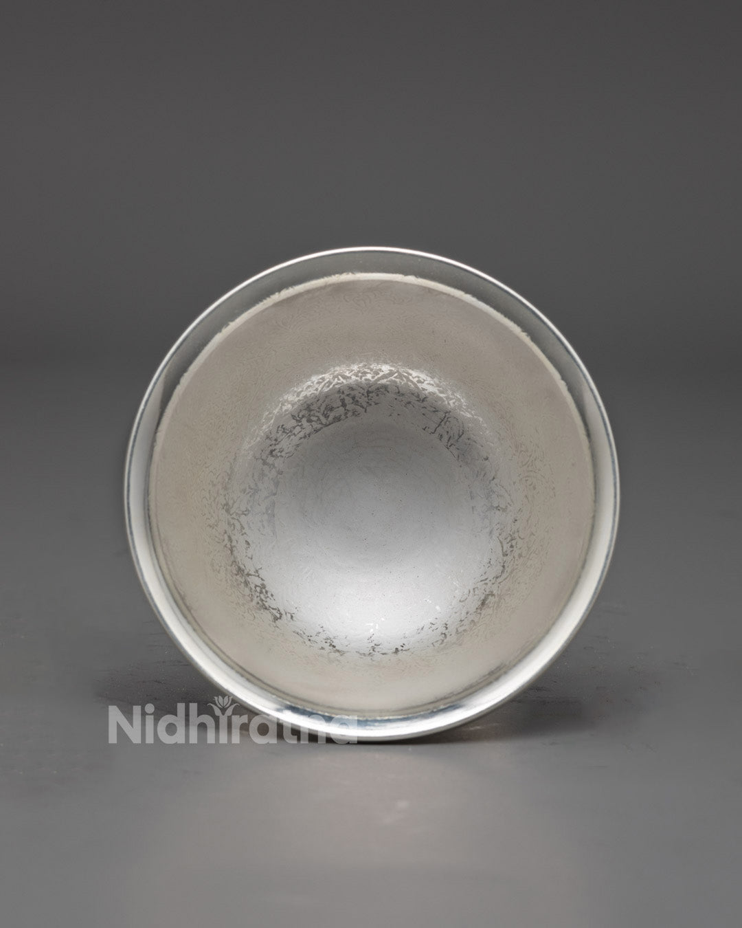 Rear view of silver water offering bowl highlighting elegant carved patterns