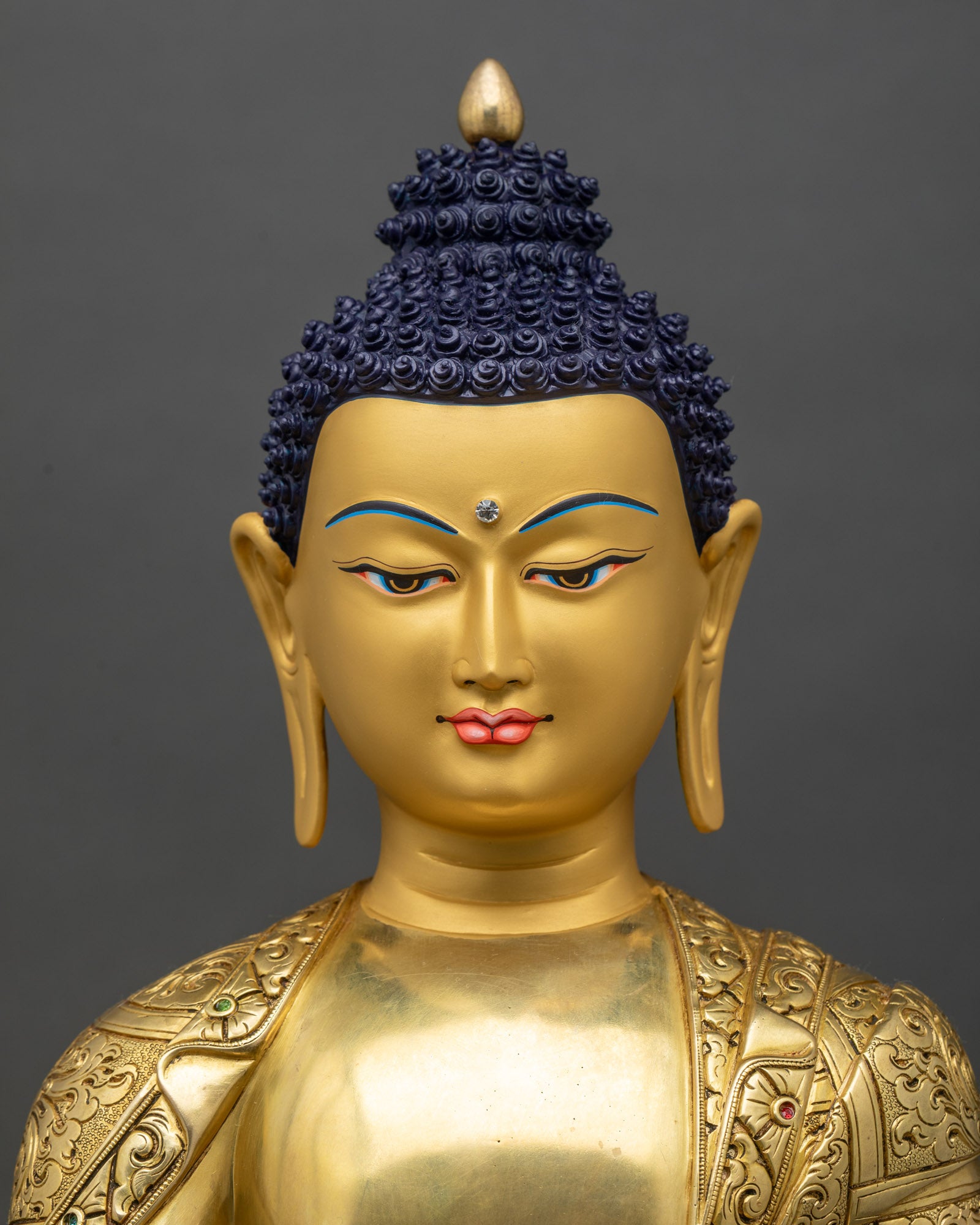 Regular close-up of Shakyamuni Buddha sculpture showing intricate gold and copper details