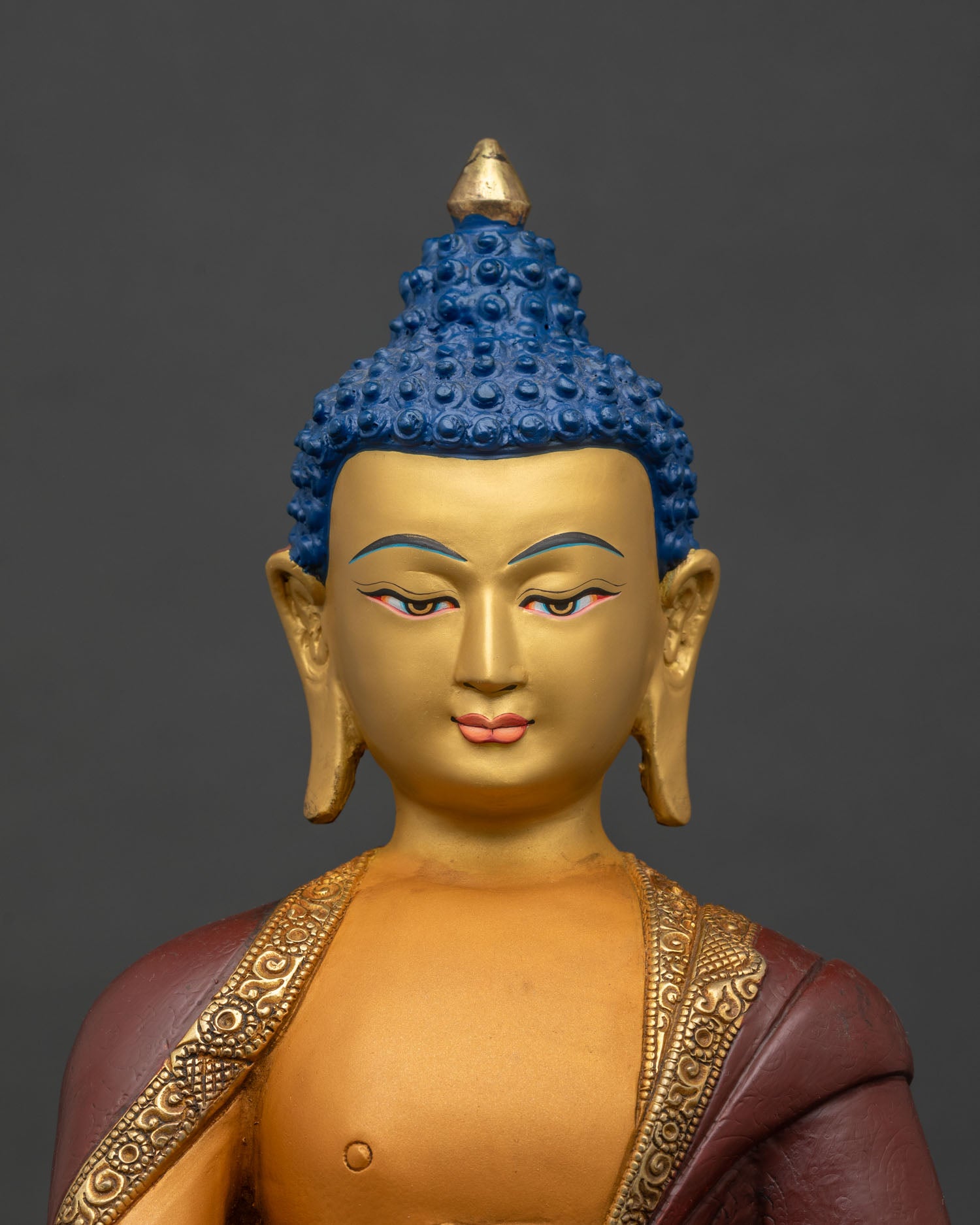 Regular close-up of Shakyamuni Buddha statue showing detailed gold-gilded robe